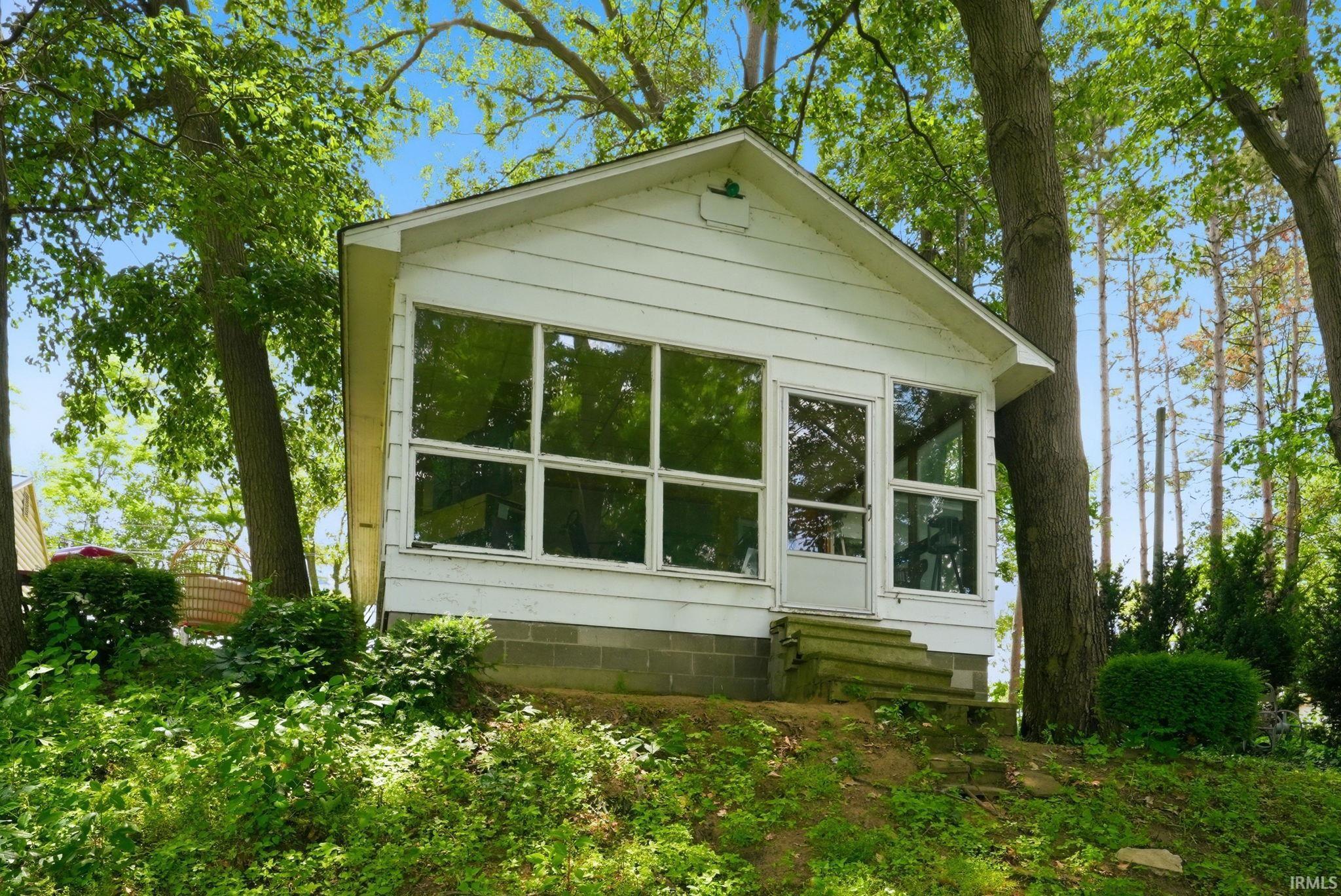 Image 0: White siding structure with a gable roof, featuring expansive glass panel windows and a glass-paneled entry door, Front Of Structure Image 0: White siding structure with a gable roof, featuring expansive glass panel windows and a glass-paneled entry door, Front Of Structure