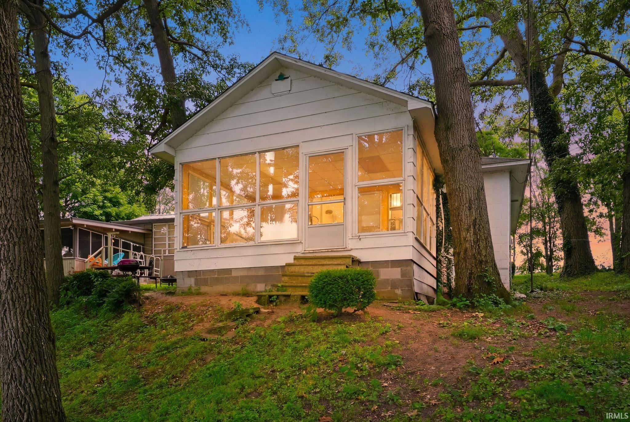 Image 1: White siding residence featuring a prominent screened-in porch with multiple windows, Front Of Structure Image 1: White siding residence featuring a prominent screened-in porch with multiple windows, Front Of Structure