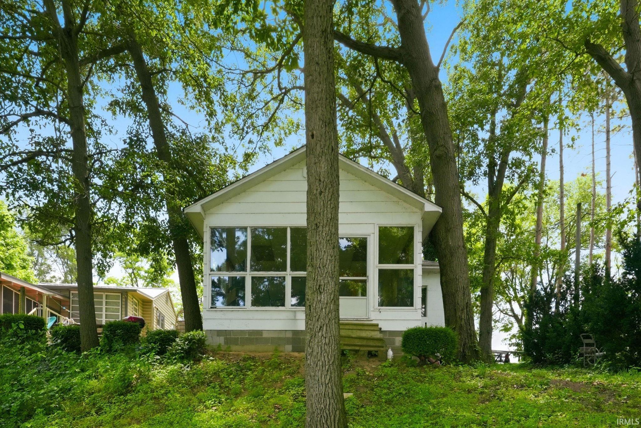 Image 3: White siding exterior featuring a prominent sunroom with multiple windows and a white entry door, Back Of Structure Image 3: White siding exterior featuring a prominent sunroom with multiple windows and a white entry door, Back Of Structure