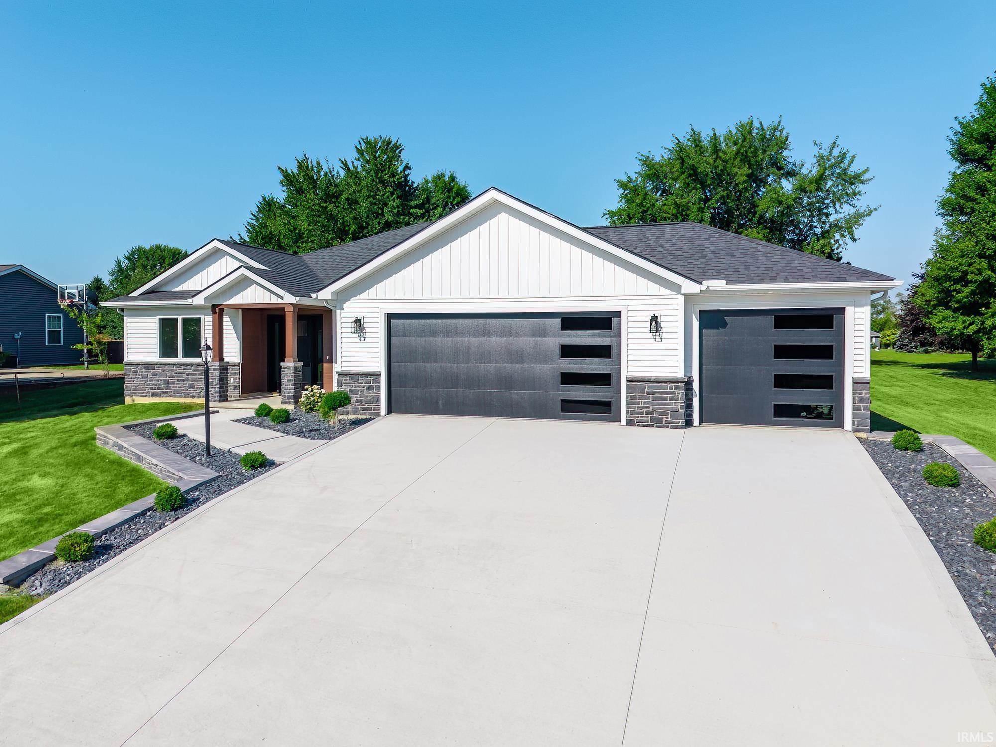 Image 1: Contemporary ranch-style residence featuring white vertical siding, dark gray horizontal garage doors with frosted glass panels, and a stone facade foundation, Front Of Structure Image 1: Contemporary ranch-style residence featuring white vertical siding, dark gray horizontal garage doors with frosted glass panels, and a stone facade foundation, Front Of Structure