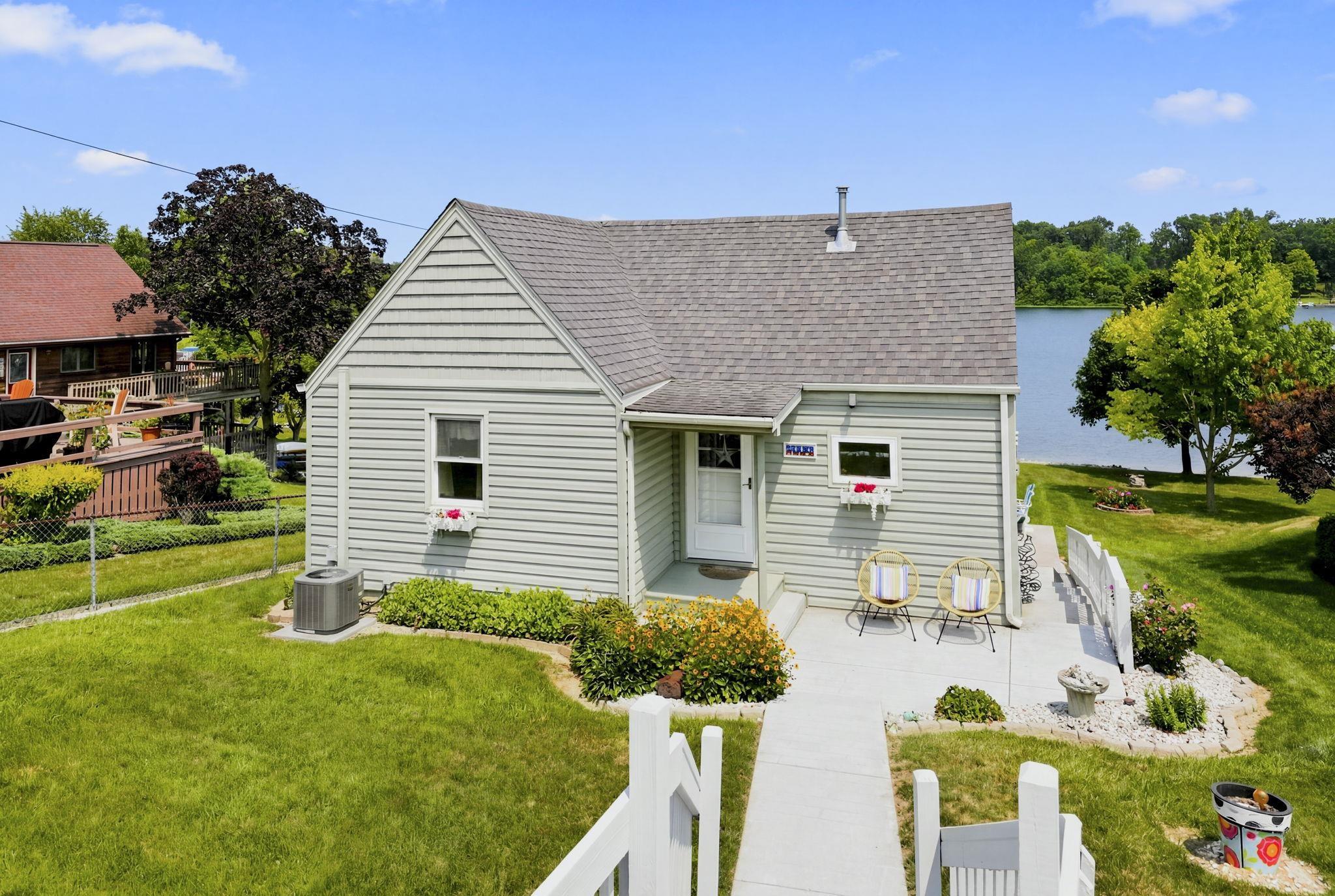 Image 0: Single-story w/walkout lwr lvl residence with light gray siding, a gabled roof, and a front patio, Street Side of Cottage Image 0: Single-story w/walkout lwr lvl residence with light gray siding, a gabled roof, and a front patio, Street Side of Cottage