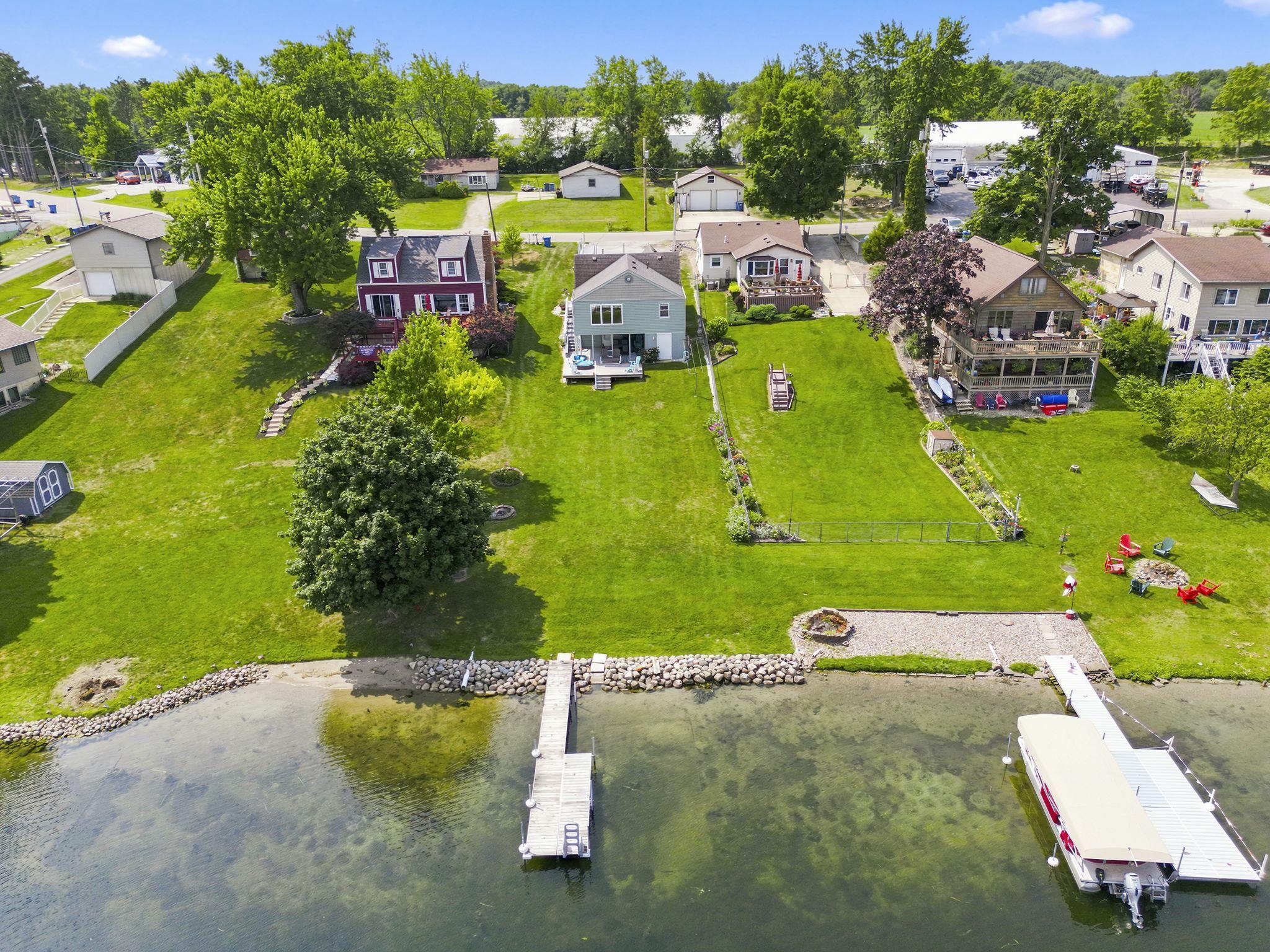 Image 2: Waterfront property featuring a private dock, stone-lined shore, and expansive green lawn, Aerial View Image 2: Waterfront property featuring a private dock, stone-lined shore, and expansive green lawn, Aerial View