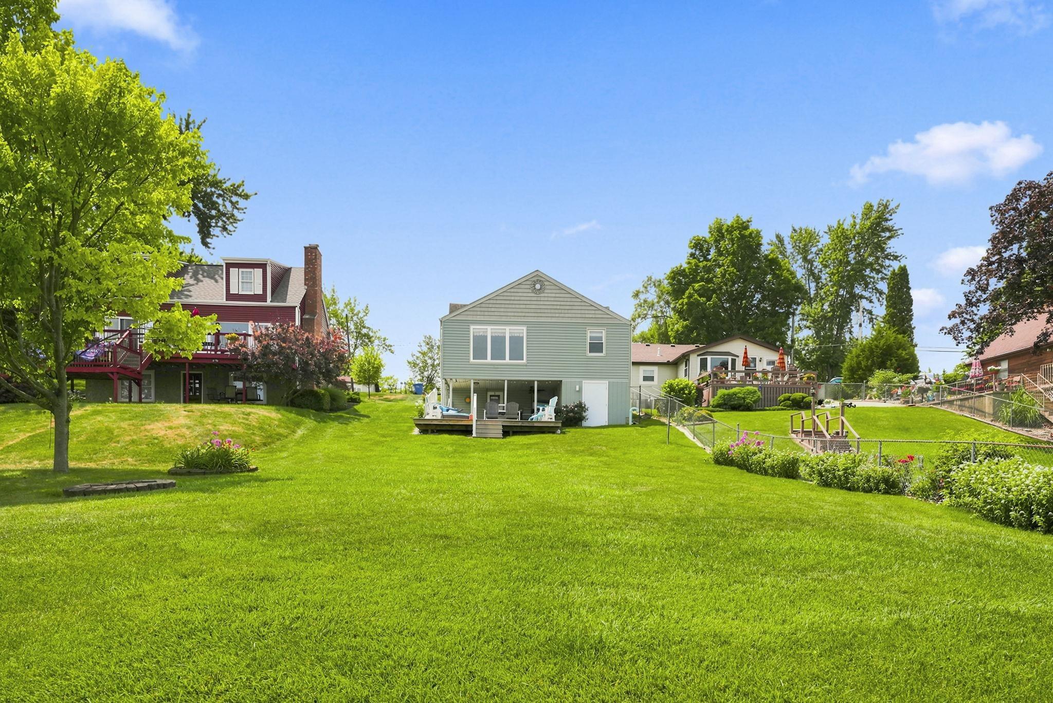 Image 3: Expansive green space featuring a gentle slope, mature trees, and a garden area and bonfire, Expansive Level front lot Image 3: Expansive green space featuring a gentle slope, mature trees, and a garden area and bonfire, Expansive Level front lot