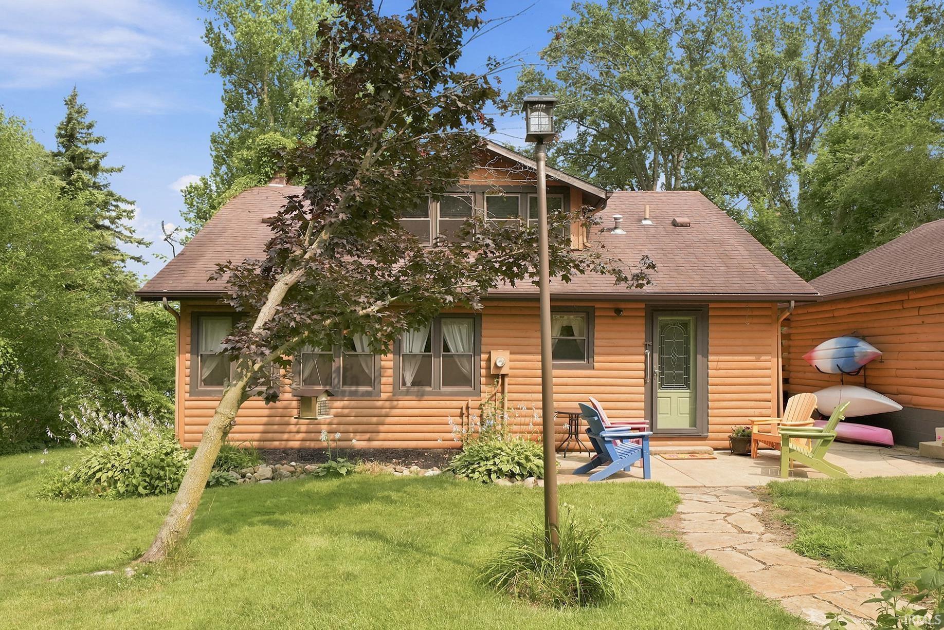 Image 3: Log-sided home featuring a light green entry door and multiple windows with brown trim, Back Of Structure Image 3: Log-sided home featuring a light green entry door and multiple windows with brown trim, Back Of Structure