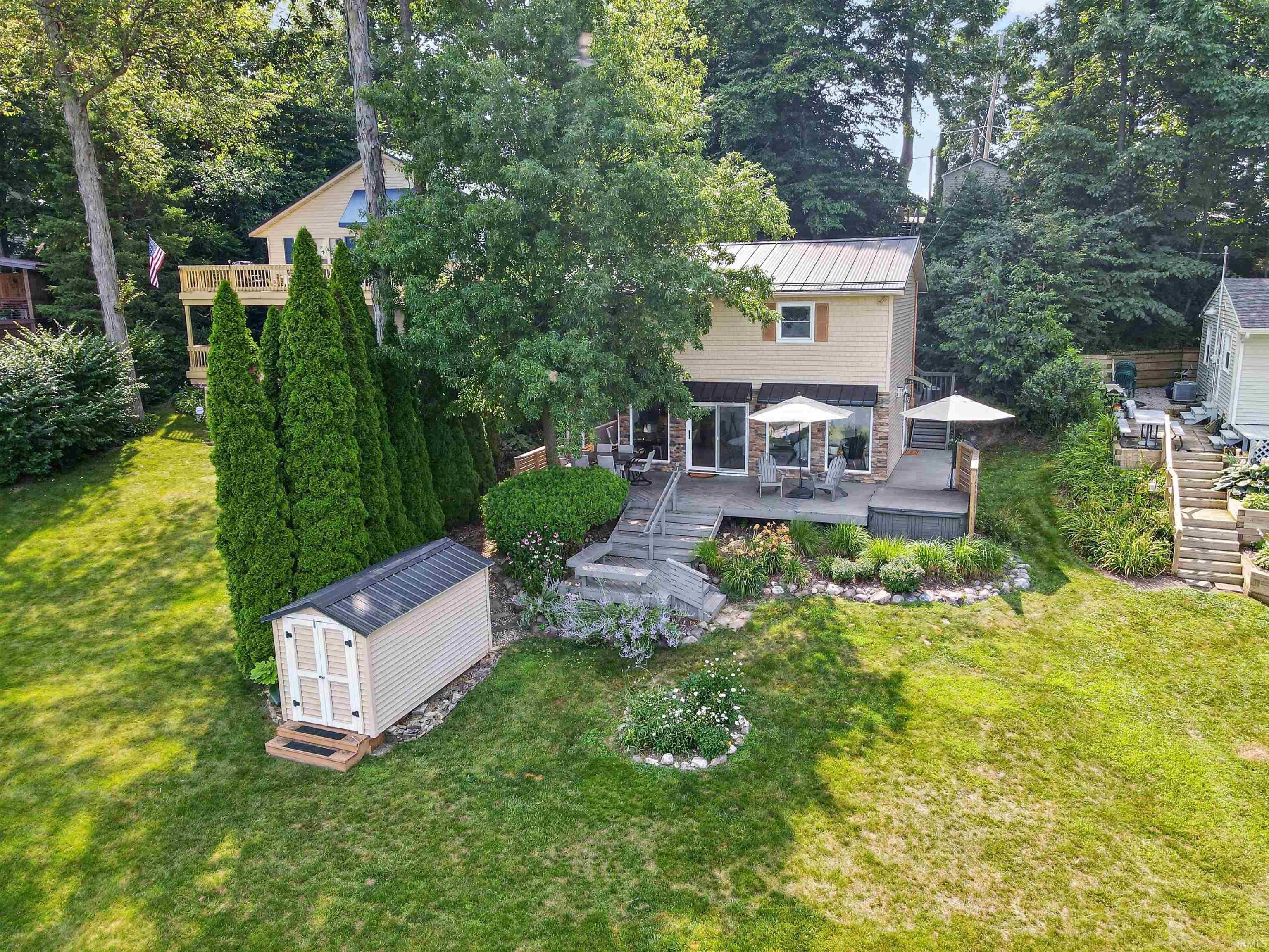 Image 1: Rear exterior featuring a multi-level deck, stone veneer accents, and a metal roof, Back Of Structure Image 1: Rear exterior featuring a multi-level deck, stone veneer accents, and a metal roof, Back Of Structure