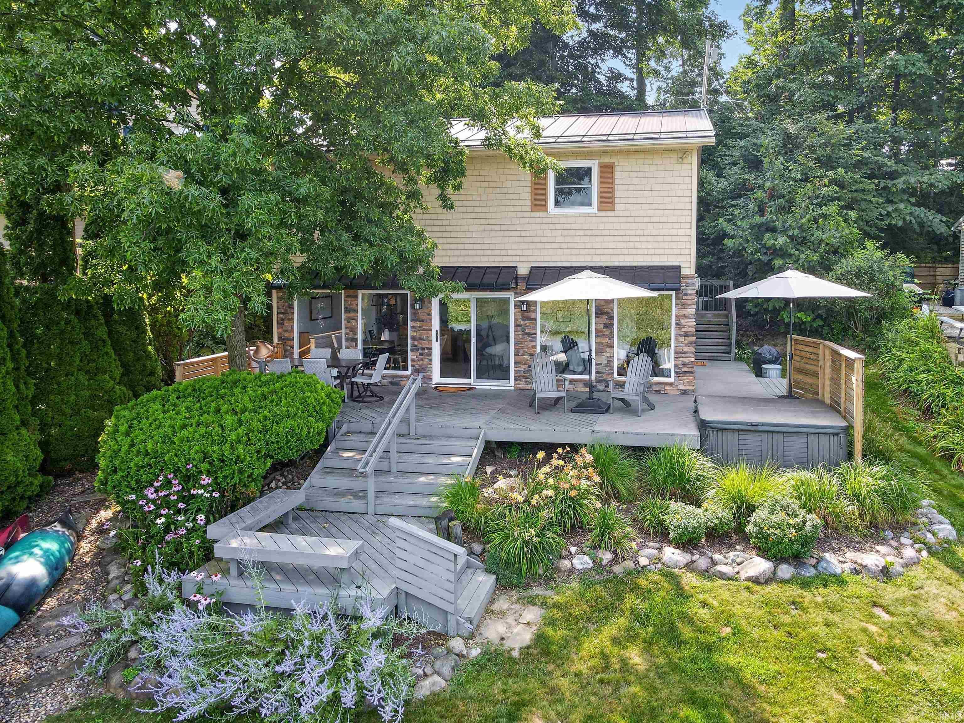 Image 2: Multi-level wood deck with a built-in spa, glass sliding doors, and natural stone veneer accents, Back Of Structure Image 2: Multi-level wood deck with a built-in spa, glass sliding doors, and natural stone veneer accents, Back Of Structure
