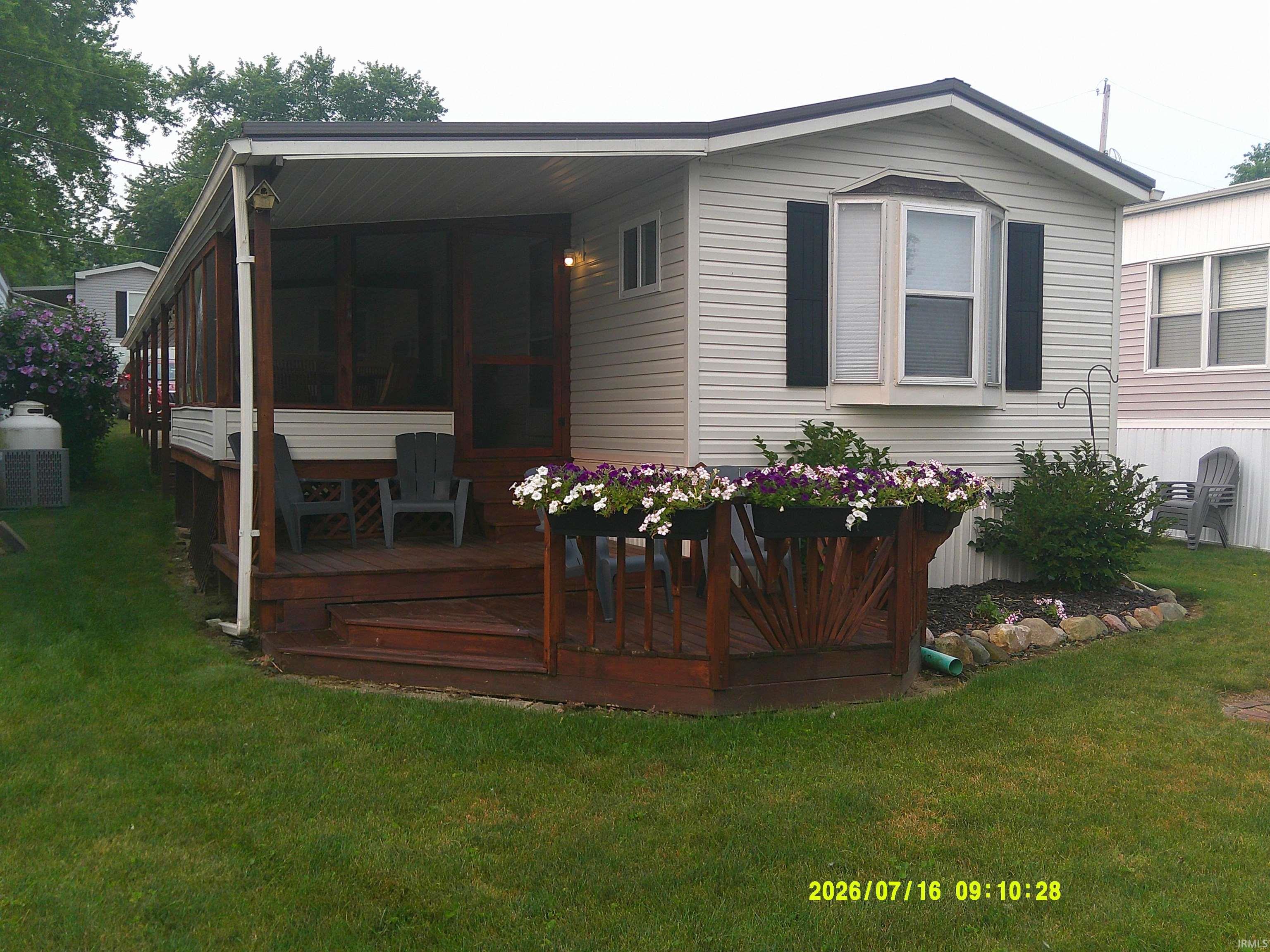 Image 0: Exterior featuring horizontal siding, a bay window with shutters, and a covered wood-finish deck, Back Of Structure Image 0: Exterior featuring horizontal siding, a bay window with shutters, and a covered wood-finish deck, Back Of Structure