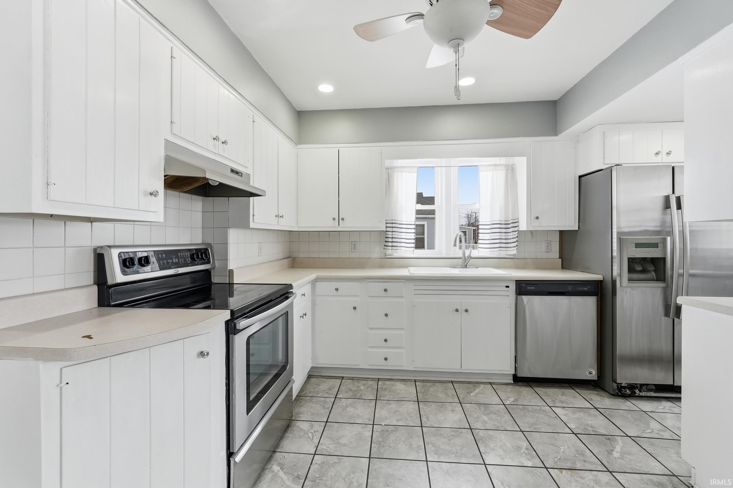 Image 3: Kitchen with appliances with stainless steel finishes, light countertops, under cabinet range hood, white cabinetry, and a ceiling fan, Kitchen
