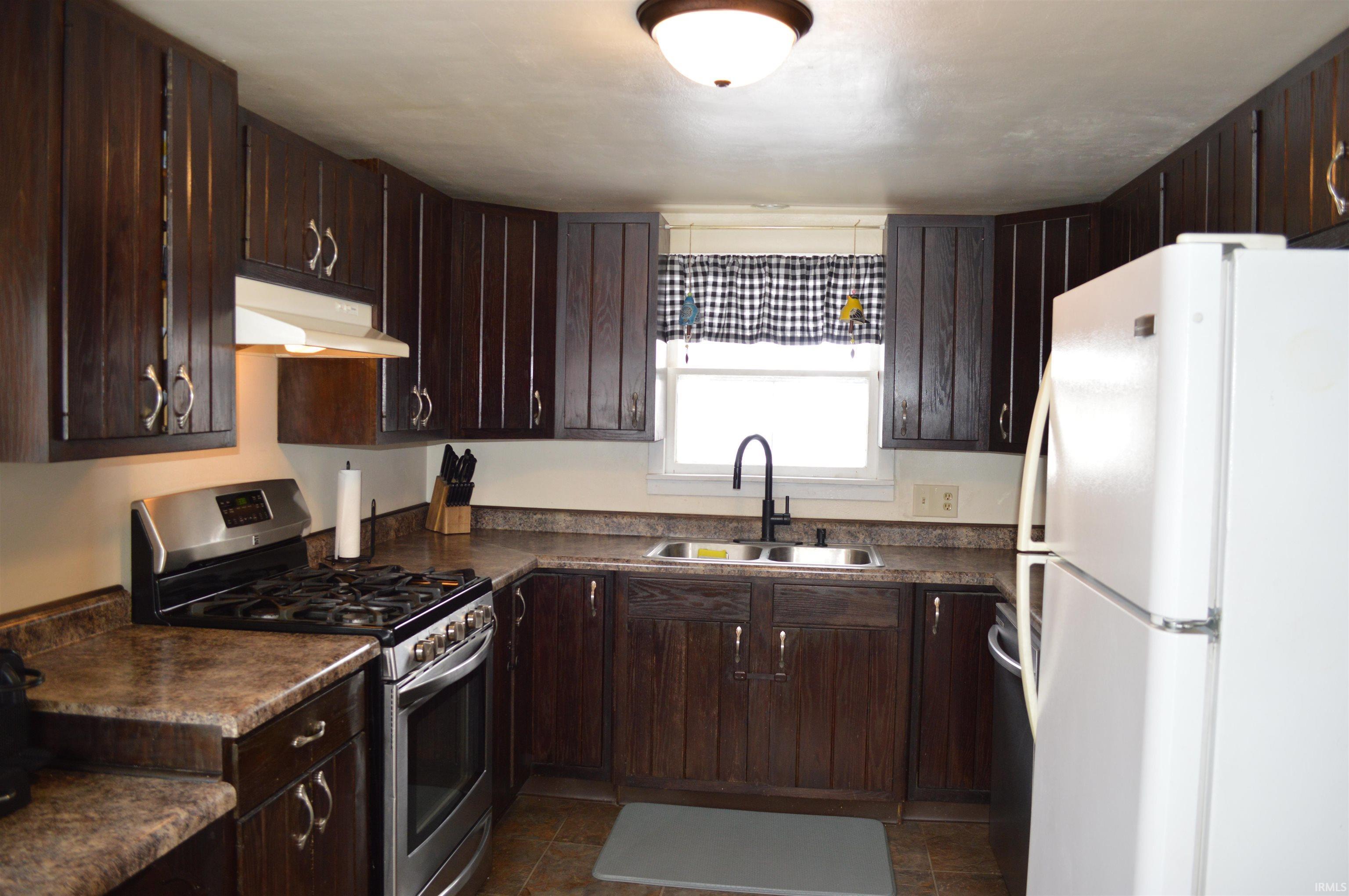 Image 3: Kitchen with stainless steel appliances, dark wood finish cabinetry, and dark countertops, Kitchen