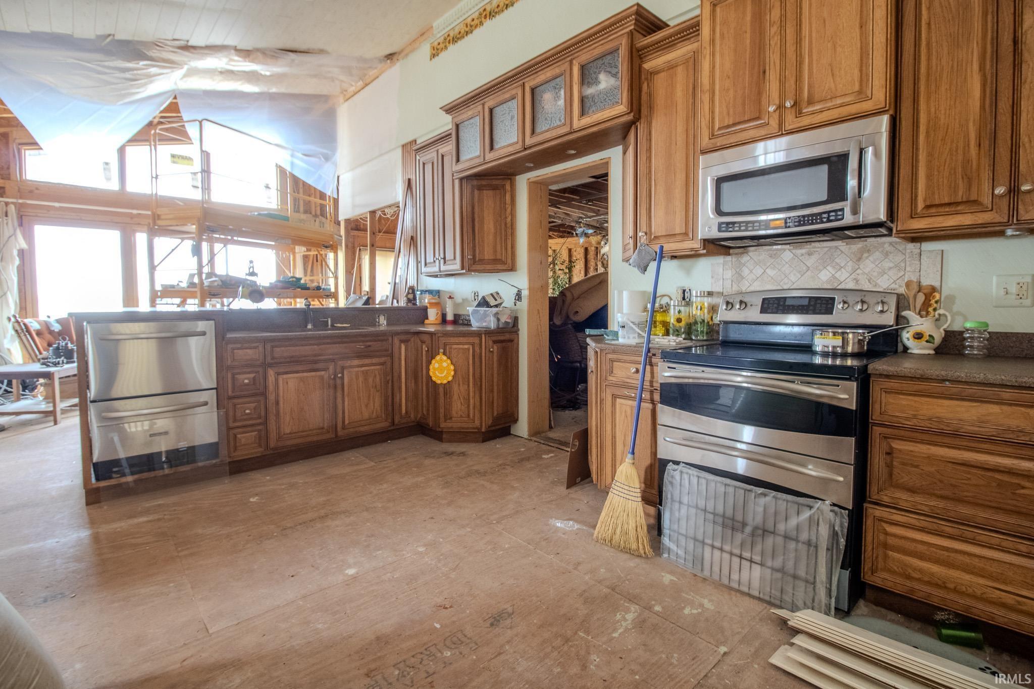 Image 1: Kitchen with stainless steel appliances, wood finish cabinets, dark countertops, glass fronted cabinets, and a peninsula, Kitchen