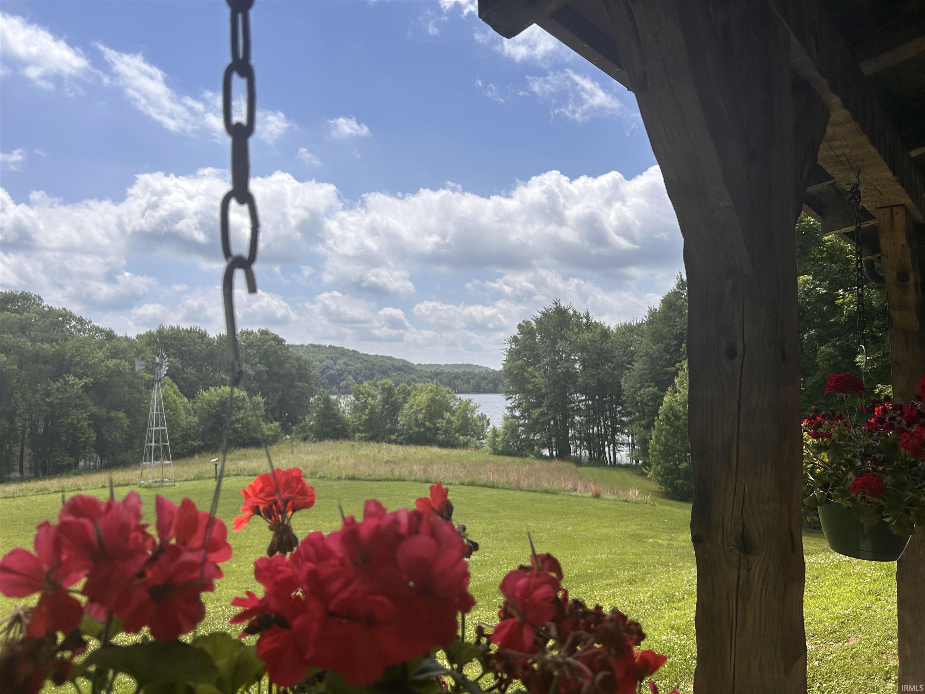 Image 1: Expansive outdoor setting featuring a distant body of water, mature trees, an open grassy area, and a rustic windmill structure, View from the front porch Image 1: Expansive outdoor setting featuring a distant body of water, mature trees, an open grassy area, and a rustic windmill structure, View from the front porch