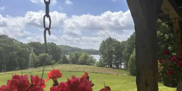 Image 1: Expansive outdoor setting featuring a distant body of water, mature trees, an open grassy area, and a rustic windmill structure, View from the front porch Image 1: Expansive outdoor setting featuring a distant body of water, mature trees, an open grassy area, and a rustic windmill structure, View from the front porch