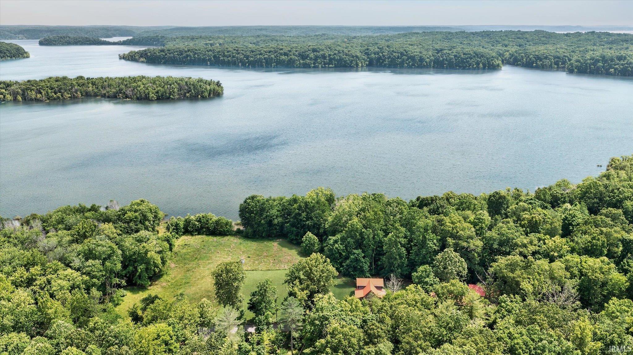 Image 2: Expansive waterfront property featuring a lake, surrounding mature woodlands, and a partially cleared land parcel, Aerial View Image 2: Expansive waterfront property featuring a lake, surrounding mature woodlands, and a partially cleared land parcel, Aerial View