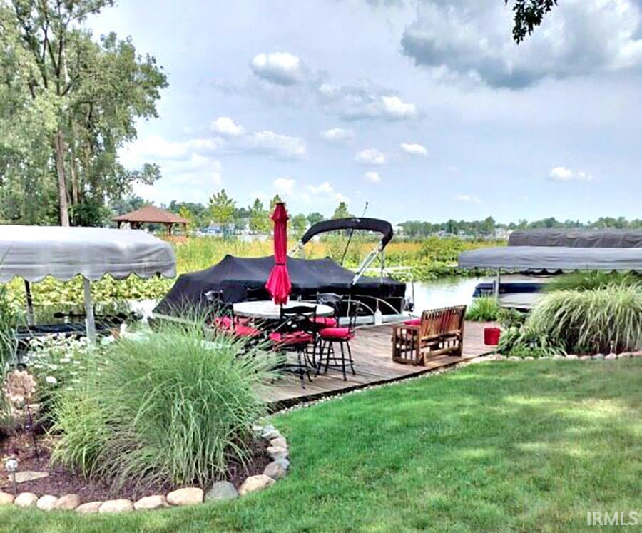 Image 2: View of green lawn featuring a deck with water view and a boat dock, Front Yard with View Image 2: View of green lawn featuring a deck with water view and a boat dock, Front Yard with View