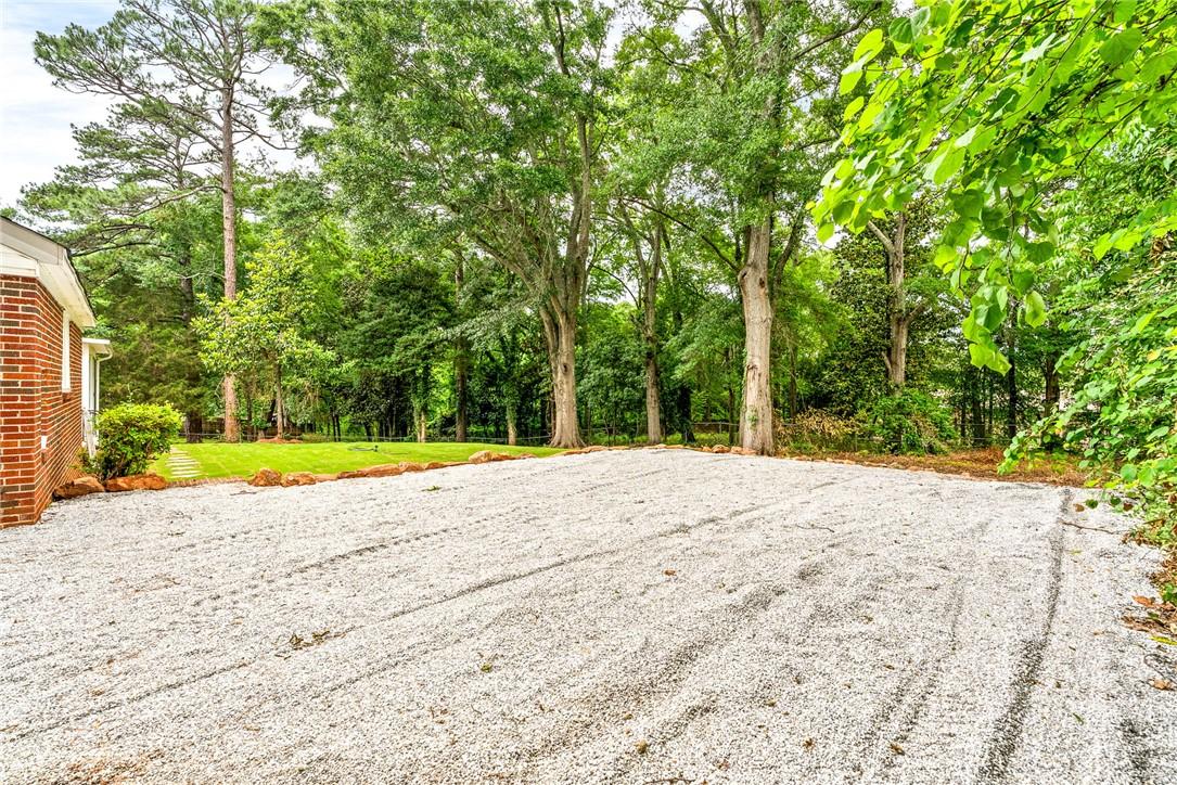 Image 3: Gravel driveway leads to a verdant lawn surrounded
