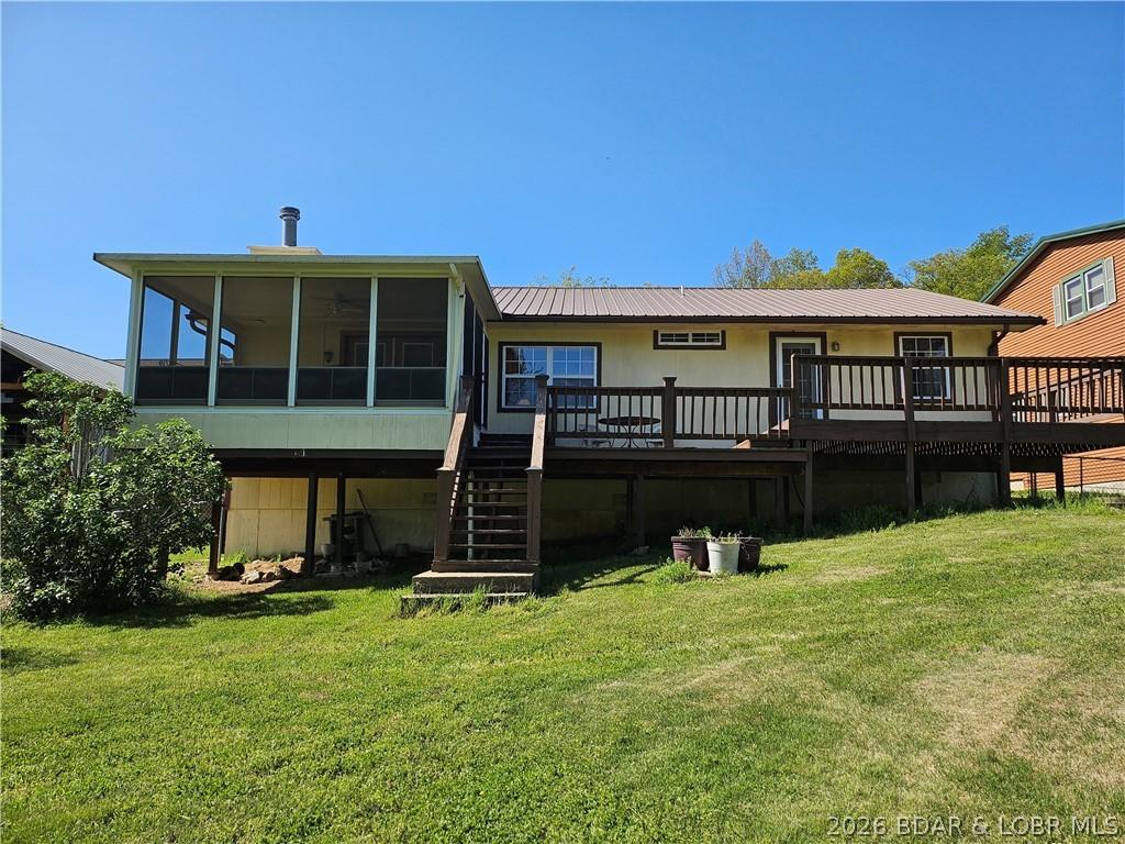 Image 1: Lakeside view of the house.  Sun room is on the le