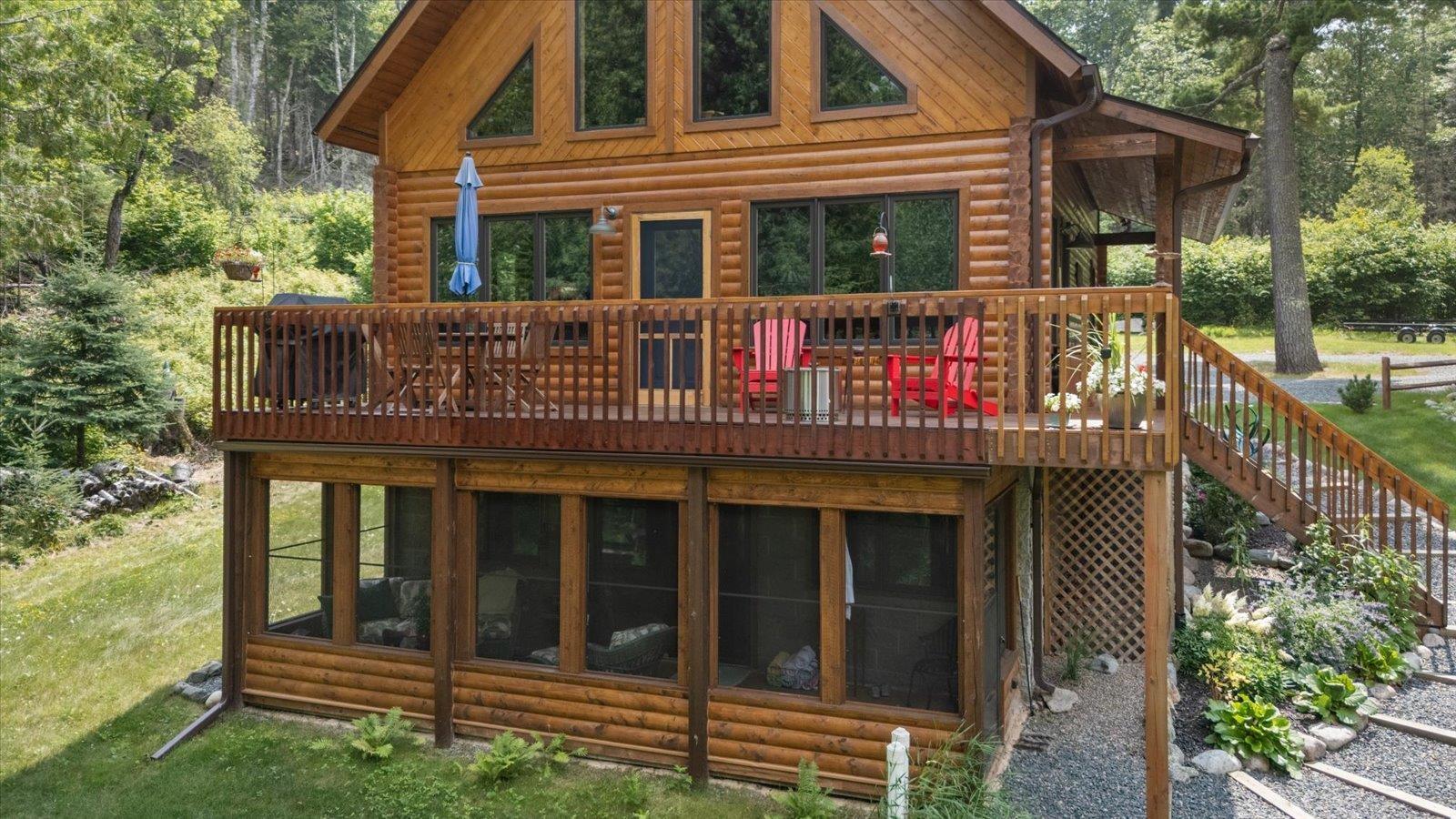 Image 0: Rear view of property featuring a sunroom, stairs, and faux log siding, Back Of Structure