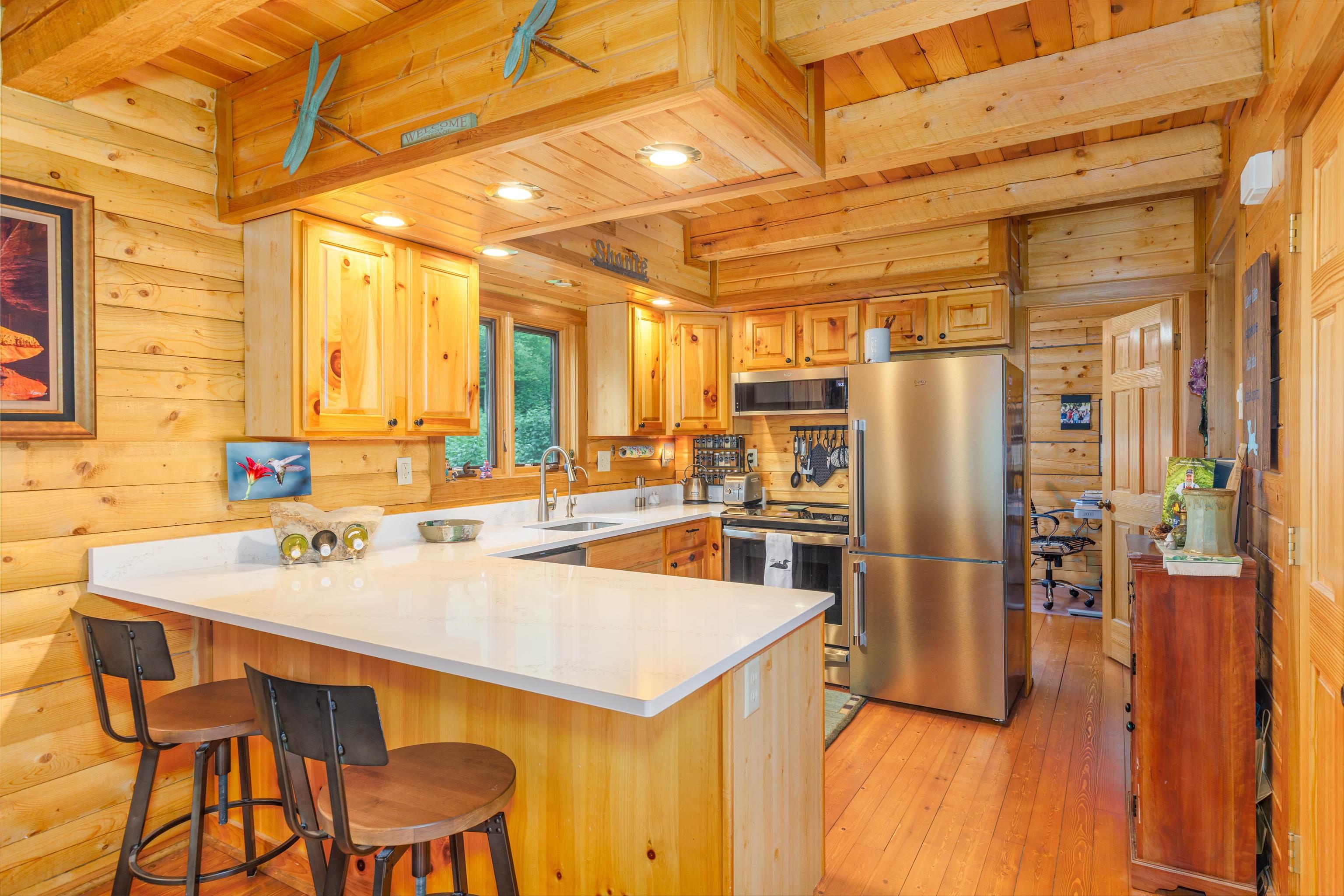 Image 1: Kitchen with a peninsula, wood ceiling, stainless steel appliances, wood walls, and a breakfast bar area, Kitchen