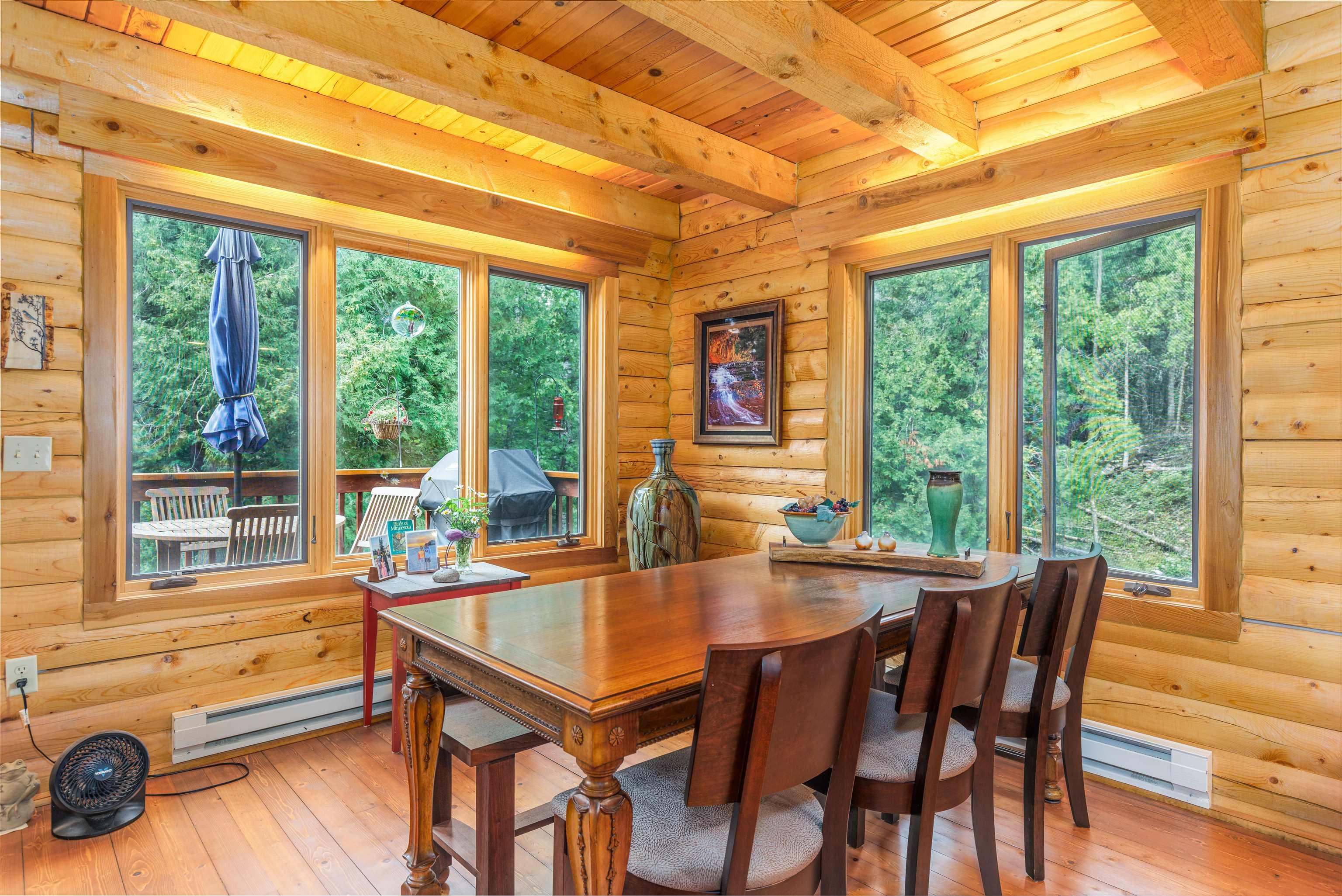 Image 3: Dining area with baseboard heating, a wooden ceiling with exposed beams, wood-type flooring, and log walls, Dining Area