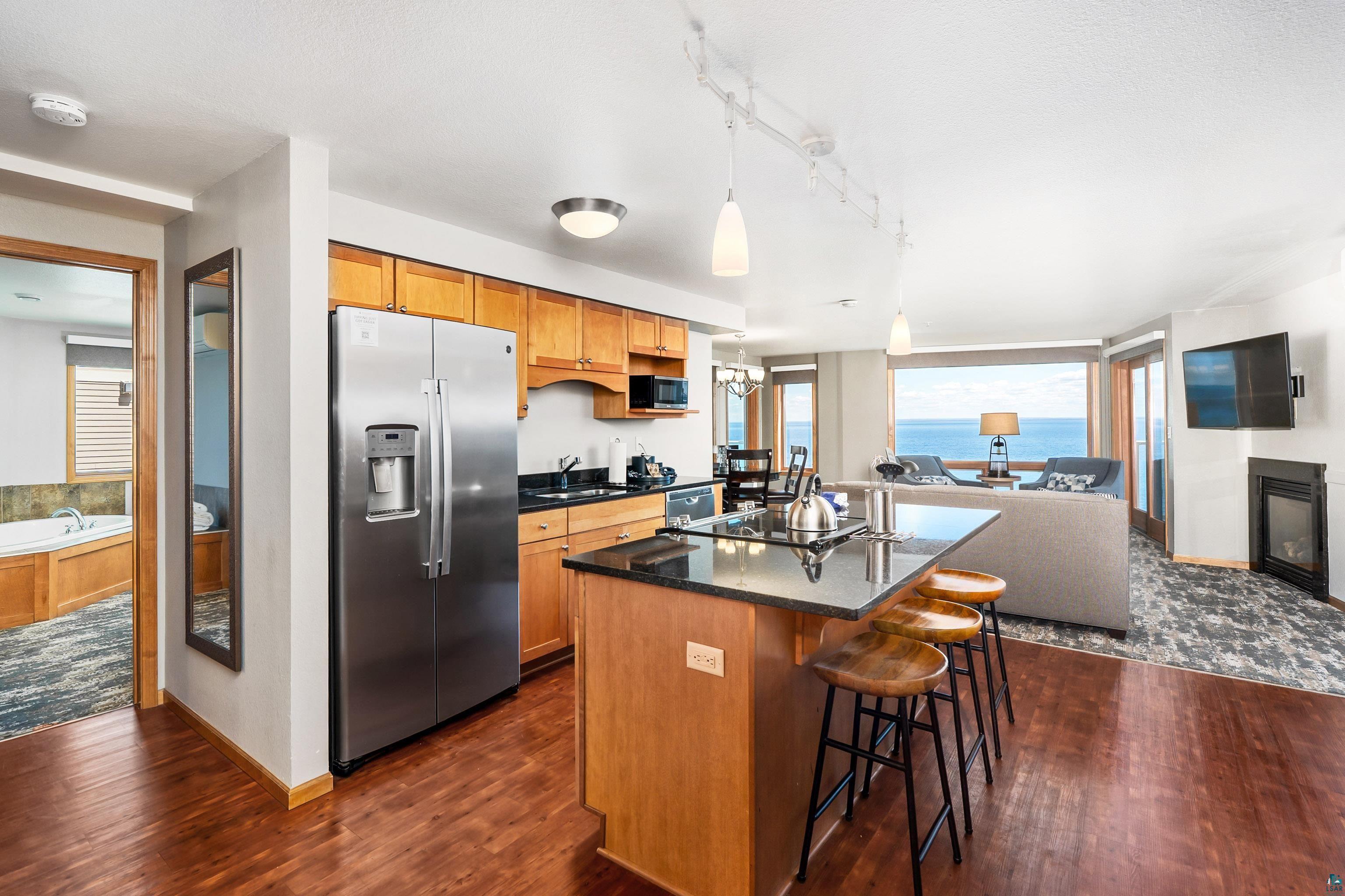 Image 3: Open-concept kitchen featuring wood cabinetry, stainless steel appliances, and a granite-topped island with seating, Kitchen