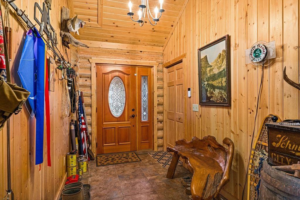 Image 3: Foyer entrance with rustic walls, lofted ceiling, wood walls, and a chandelier, Entrance Foyer