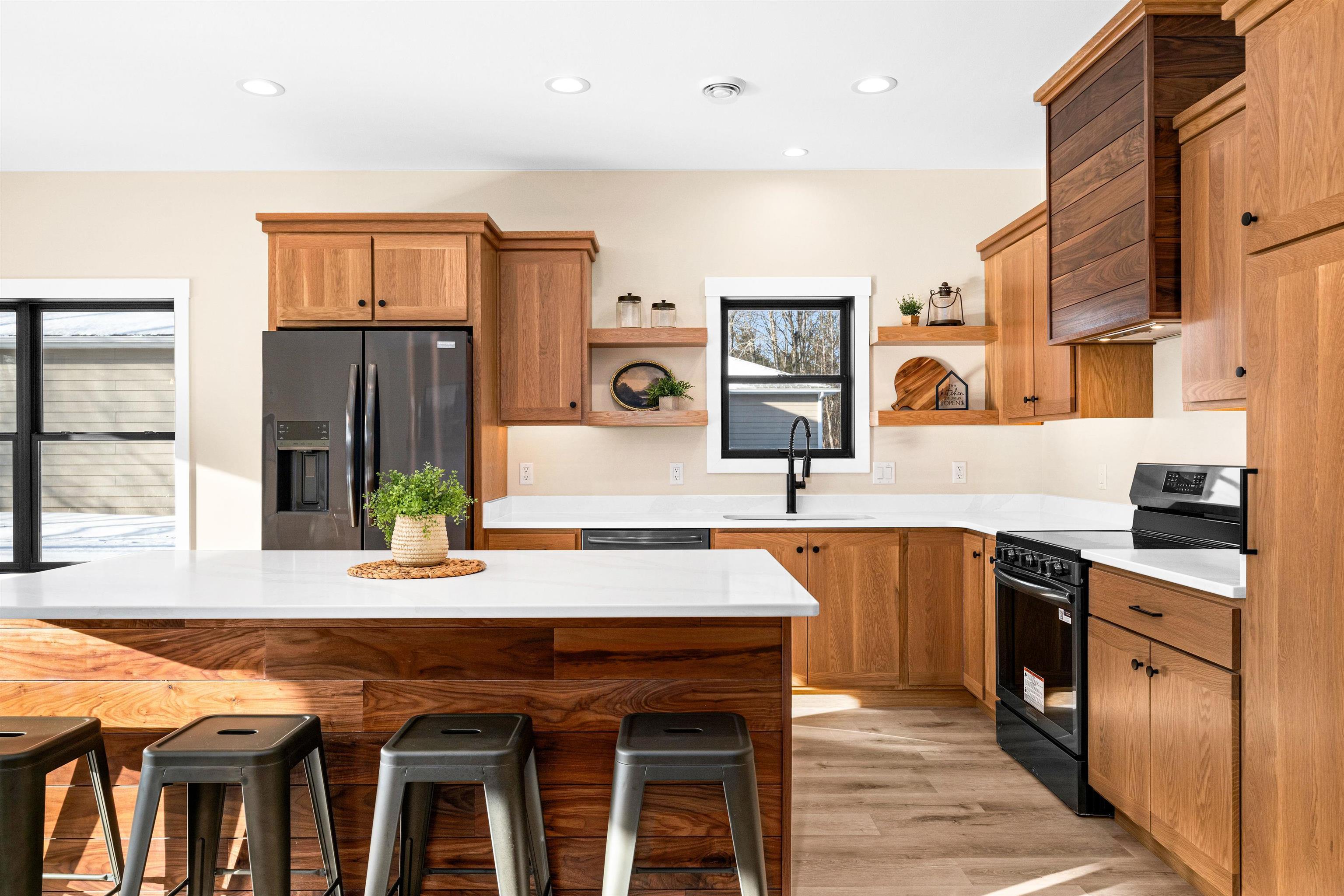 Image 3: Kitchen with black electric range oven, brown cabinets, stainless steel fridge, a breakfast bar, and recessed lighting, Kitchen