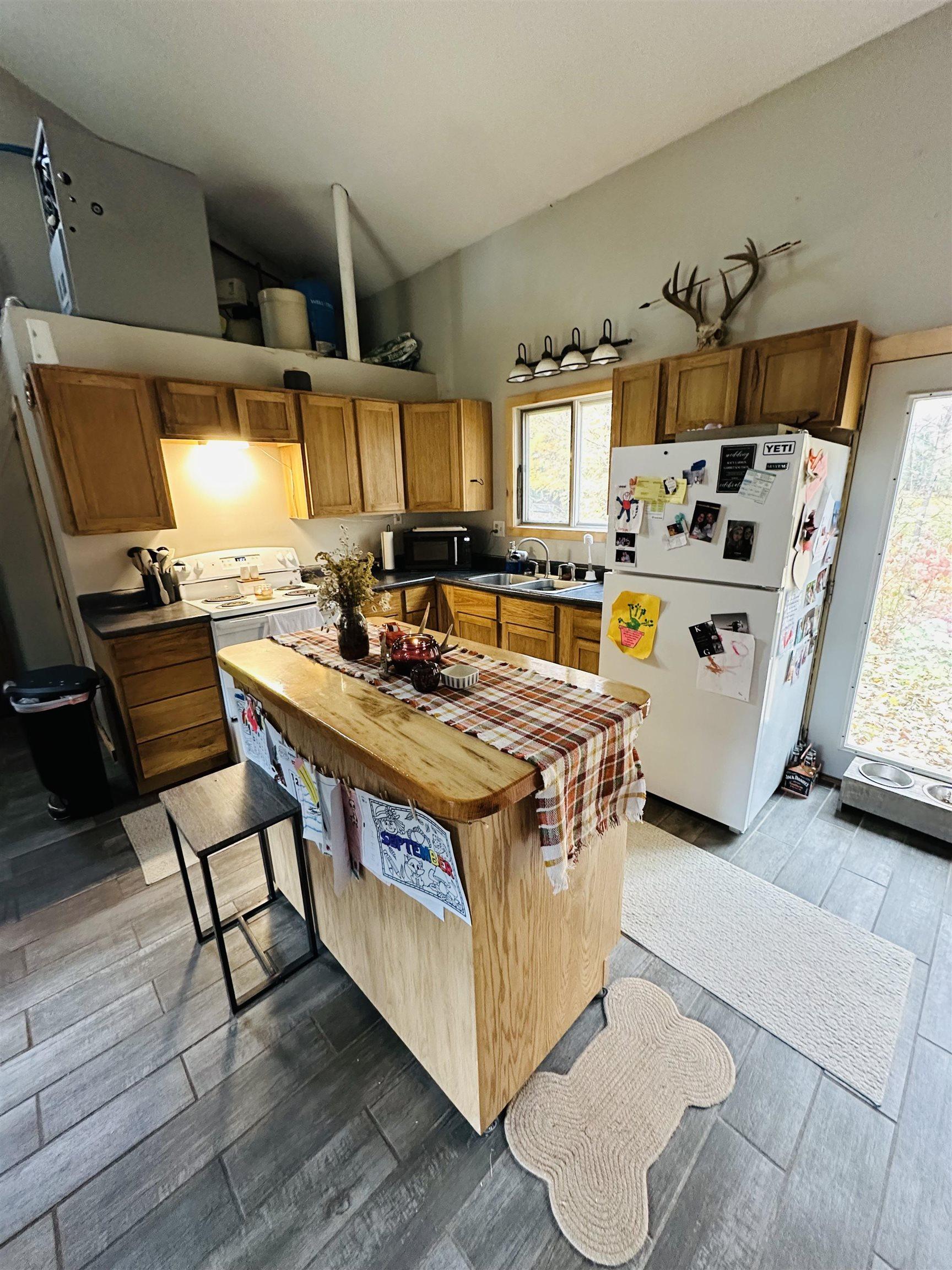Image 1: Kitchen featuring freestanding refrigerator, healthy amount of natural light, lofted ceiling, dark wood-style flooring, and butcher block countertops, Kitchen