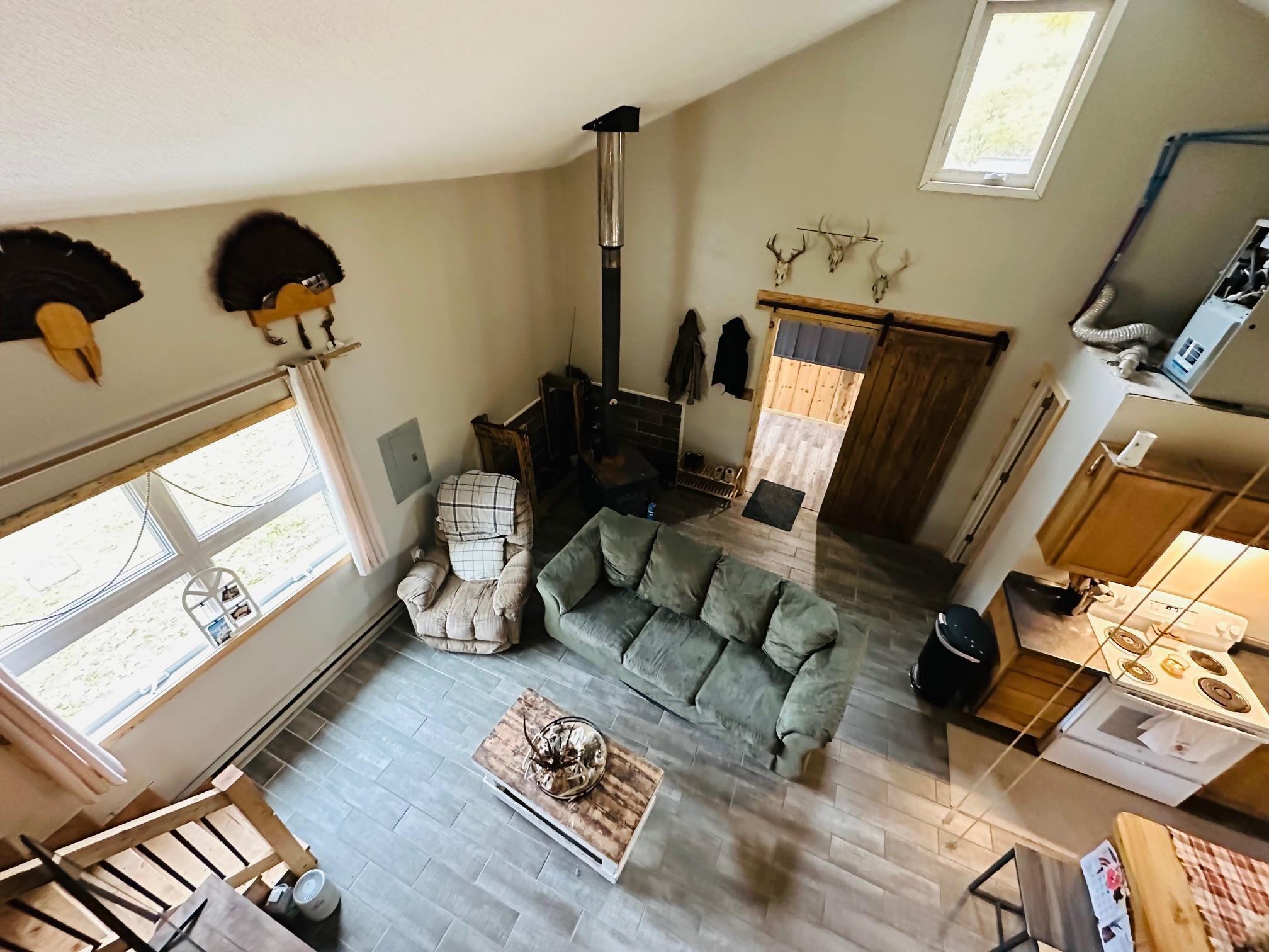 Image 3: Living room featuring wood finished floors, a wood stove, and vaulted ceiling, Living Room