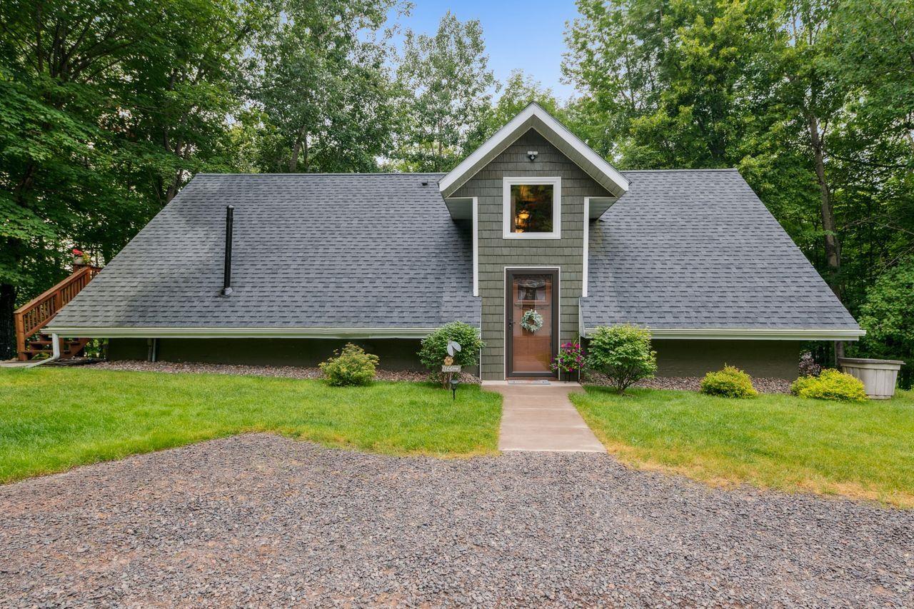 Image 1: View of front of home featuring view of wooded area, a front yard, and a shingled roof, Front Of Structure