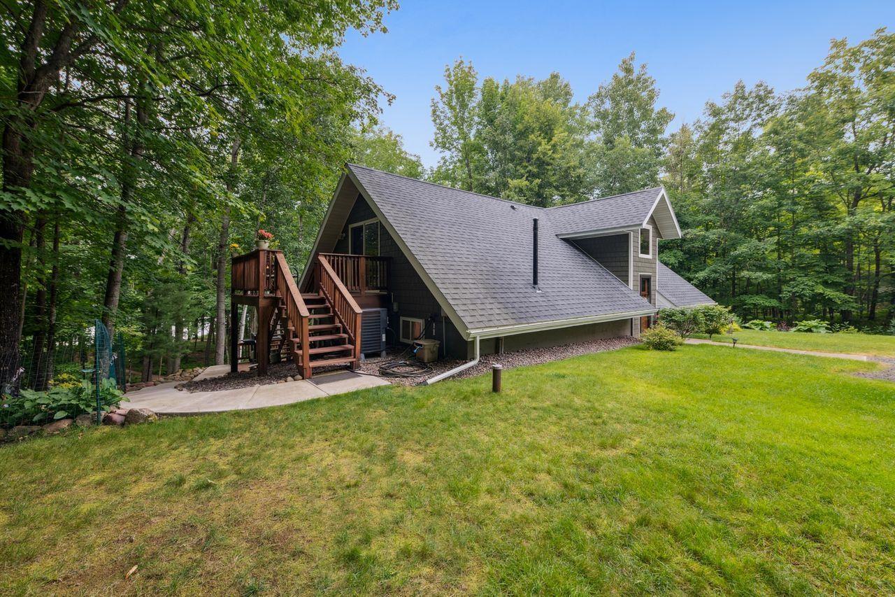 Image 2: View of side of home with a lawn, stairway, a shingled roof, and a deck, Side Of Structure