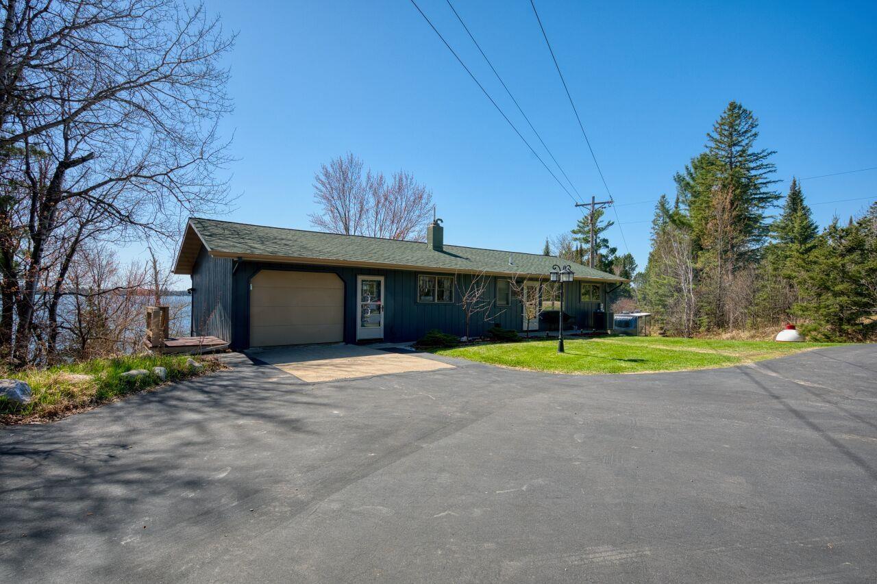 Image 2: Single story home with an attached garage, a chimney, aphalt driveway, board and batten siding, and a front yard, Front Of Structure