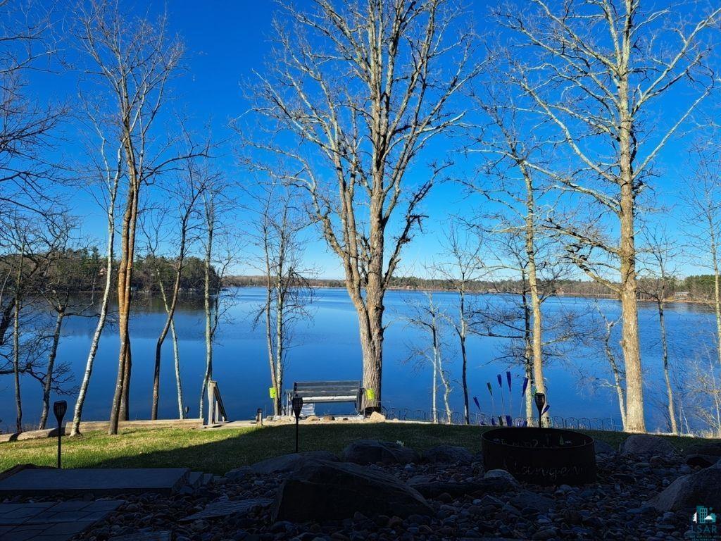 Image 1: Expansive waterfront setting featuring a tranquil lake, mature trees, a manicured lawn, and a fire pit, View