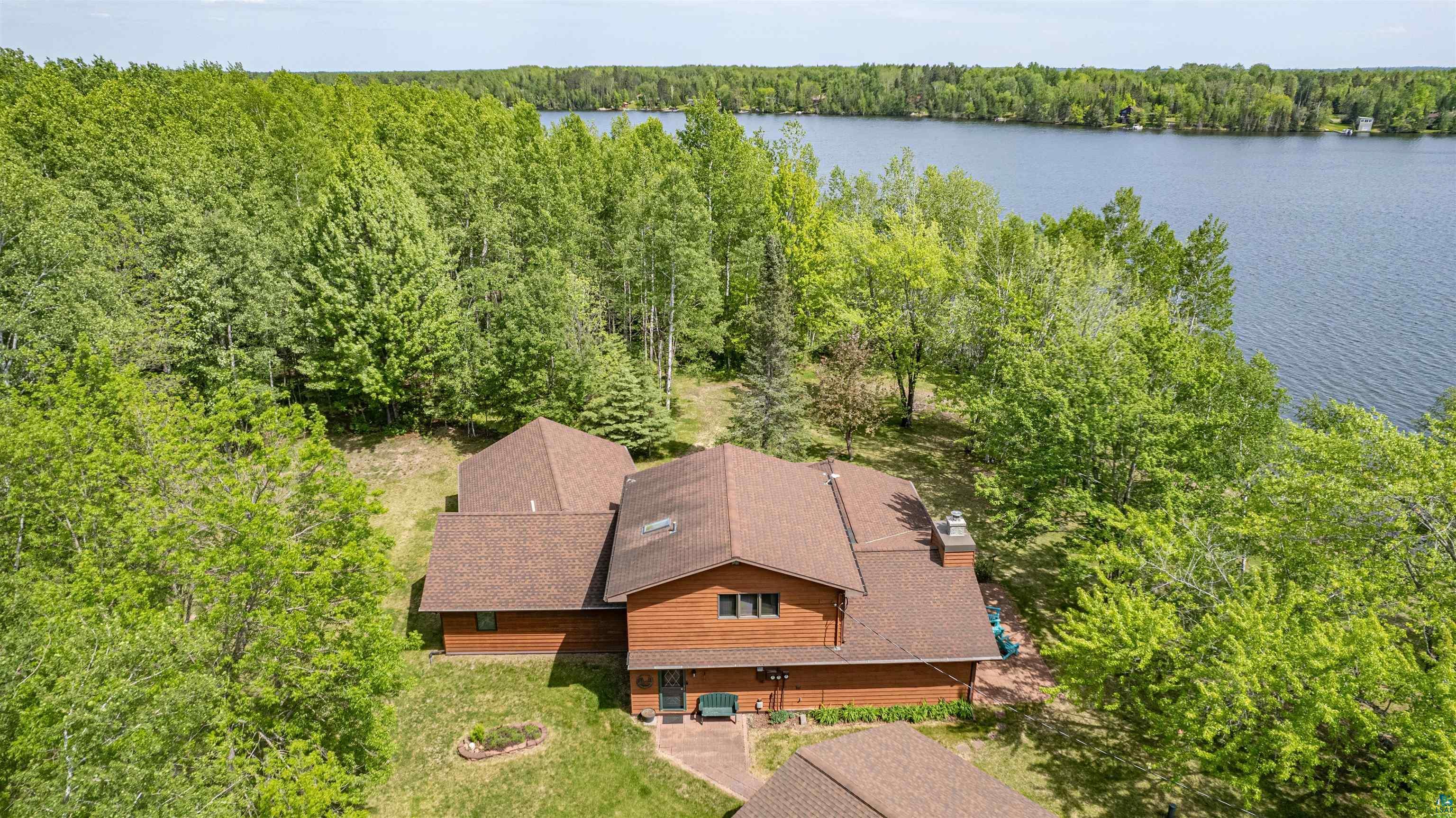 Image 1: Wood-sided residence with multiple rooflines, a prominent chimney, and a surrounding natural landscape, Aerial View