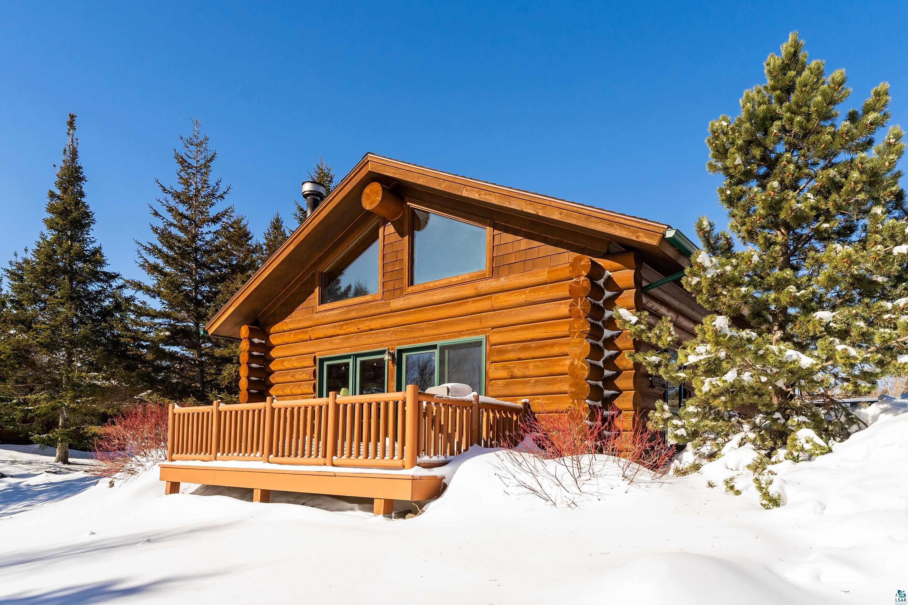 Image 0: Snow covered house featuring log exterior and a deck, Back Of Structure