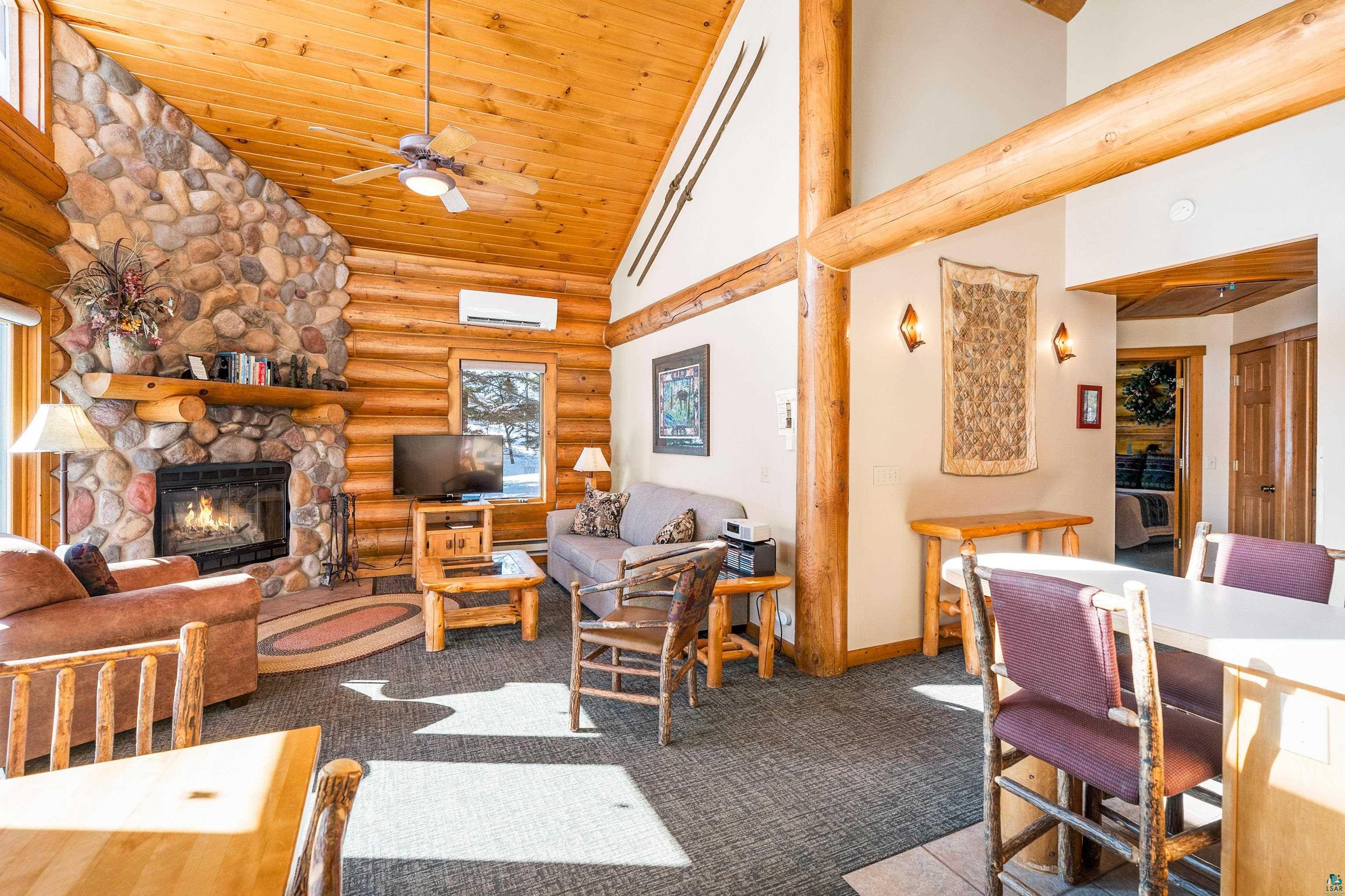 Image 2: Living room with rustic walls, a fireplace, a vaulted wood ceiling, carpet flooring, and ceiling fan, Living Room