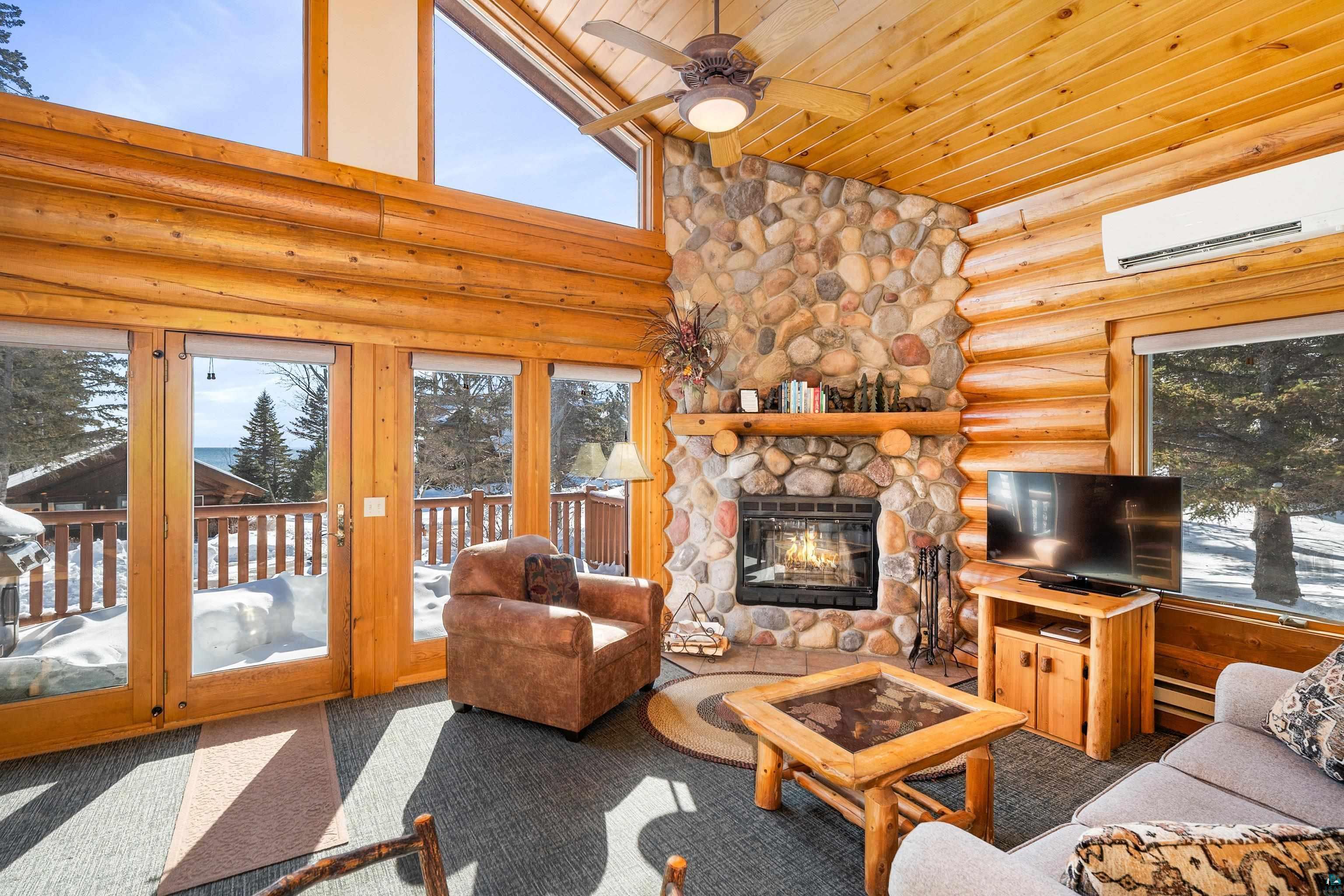 Image 3: Living room with rustic walls, carpet floors, a ceiling fan, a high wooden ceiling, and a stone fireplace, Living Room