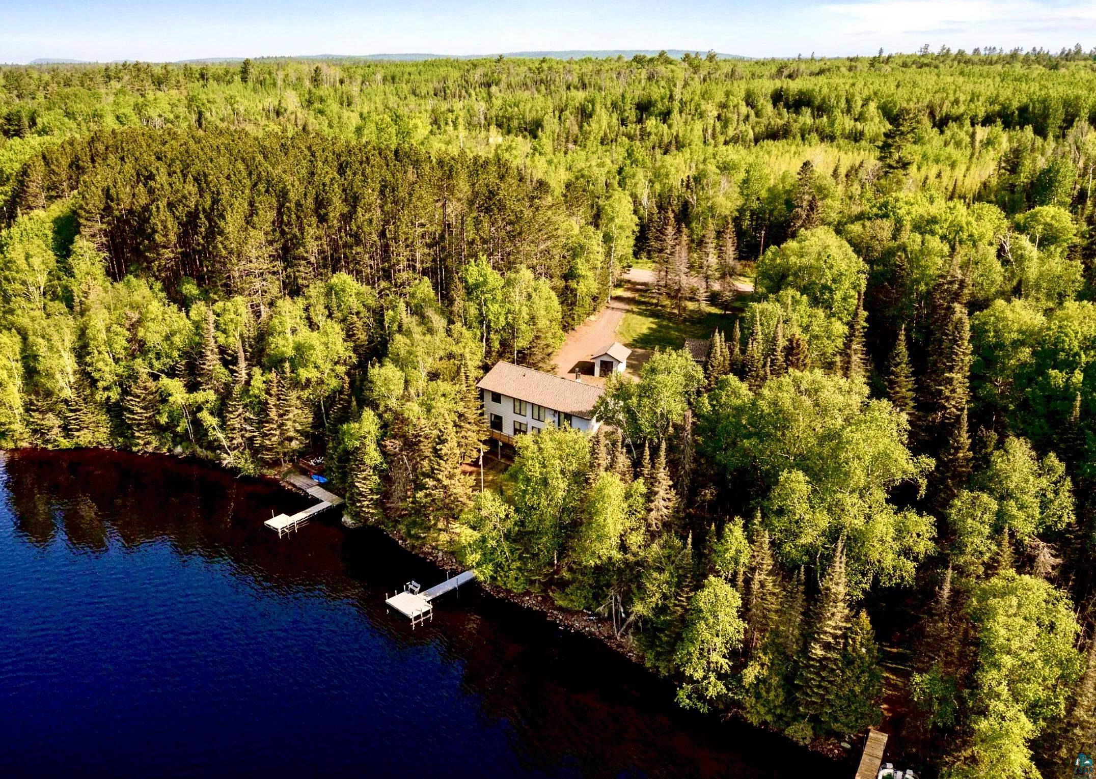 Image 0: Aerial front view of property and Devil Track Lake surrounding area with forest, Front