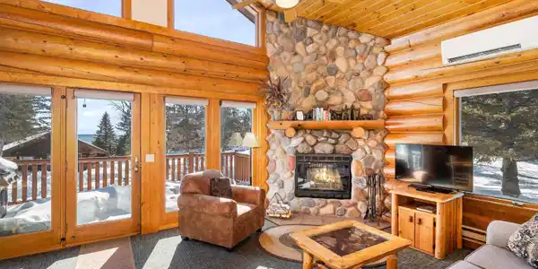 Image 3: Living room with rustic walls, carpet floors, a ceiling fan, a high wooden ceiling, and a stone fireplace, Living Room