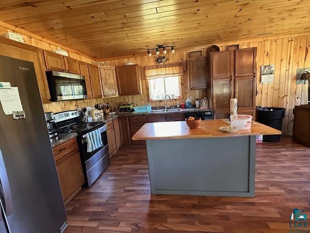 Image 2: Kitchen with appliances with stainless steel finishes, a center island, wood walls, dark wood-style floors, and wood ceiling, Kitchen