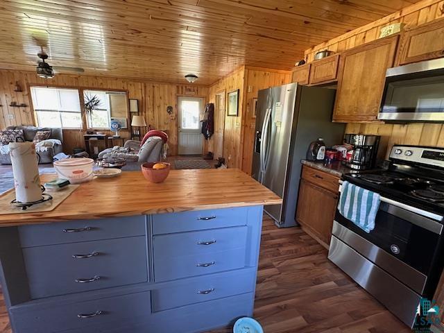 Image 3: Kitchen featuring appliances with stainless steel finishes, butcher block countertops, open floor plan, wood walls, and dark wood finished floors, Kitchen
