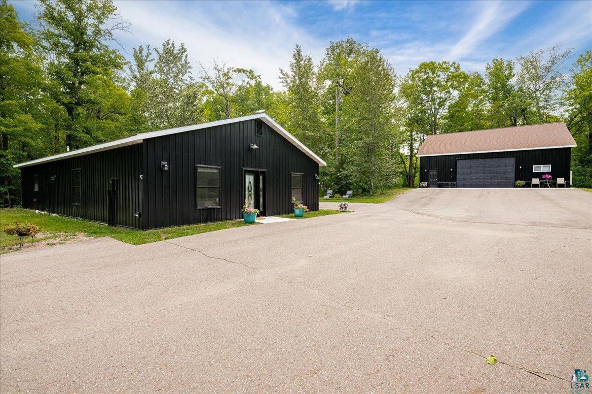 Image 1: Two distinct structures with black vertical siding and white trim, Front Of Structure
