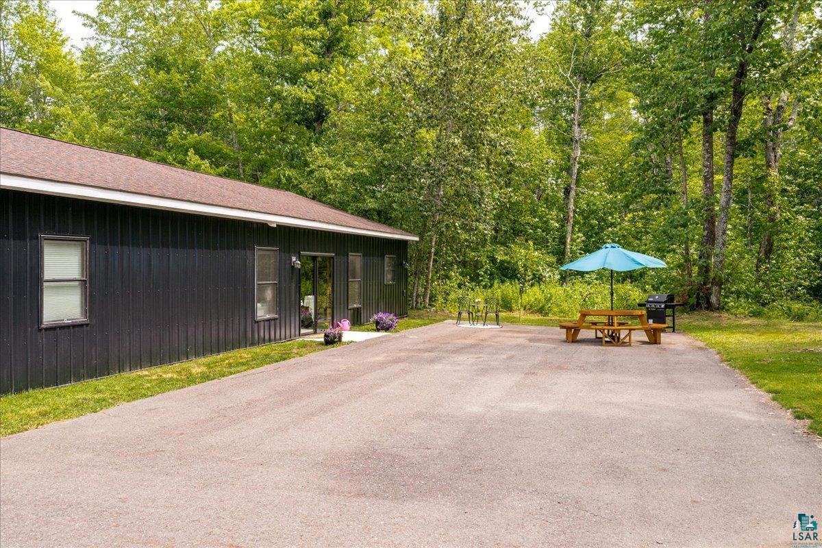 Image 3: Exterior featuring dark vertical siding, multiple windows, a sliding glass door, and a brown shingle roof, Patio