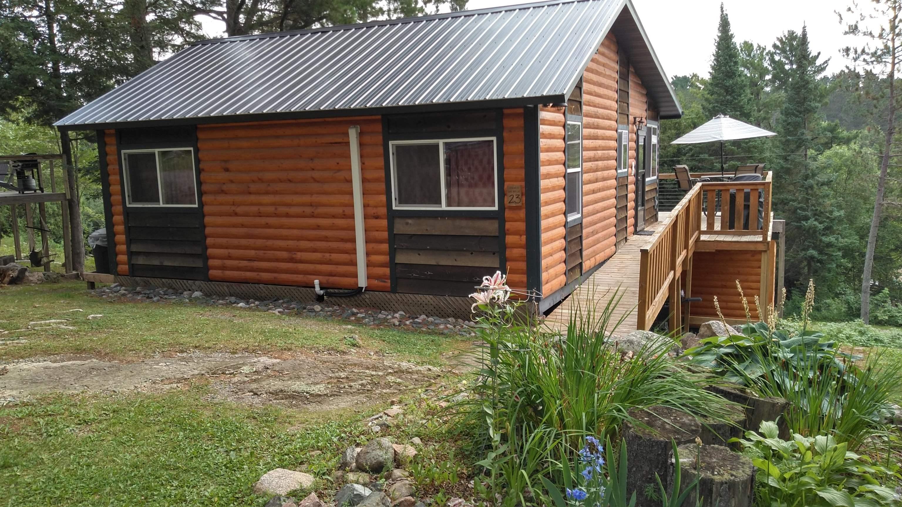 Image 0: View of side of home with faux log siding, a deck, and a metal roof, Side Of Structure