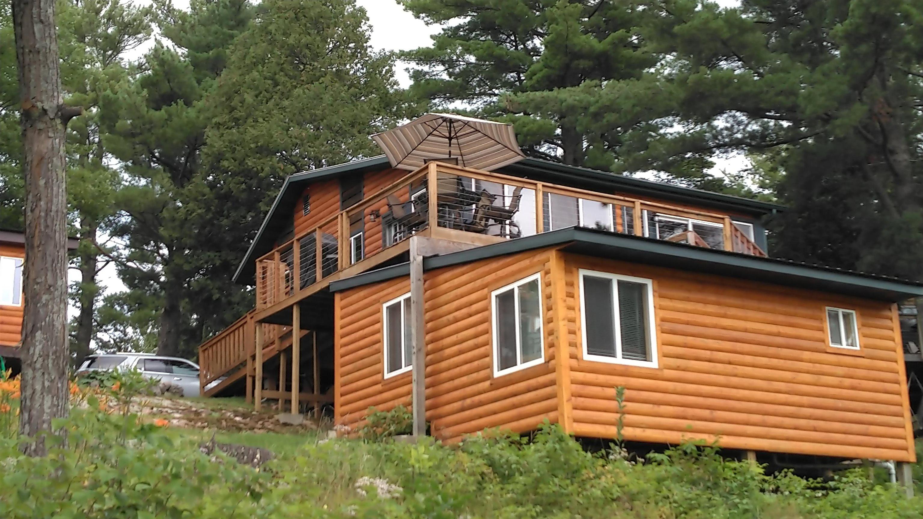Image 1: View of side of home featuring log veneer siding and a deck, Side Of Structure