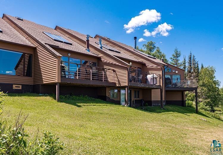 Image 0: Rear view of property featuring roof mounted solar panels, a lawn, and a balcony, Back Of Structure