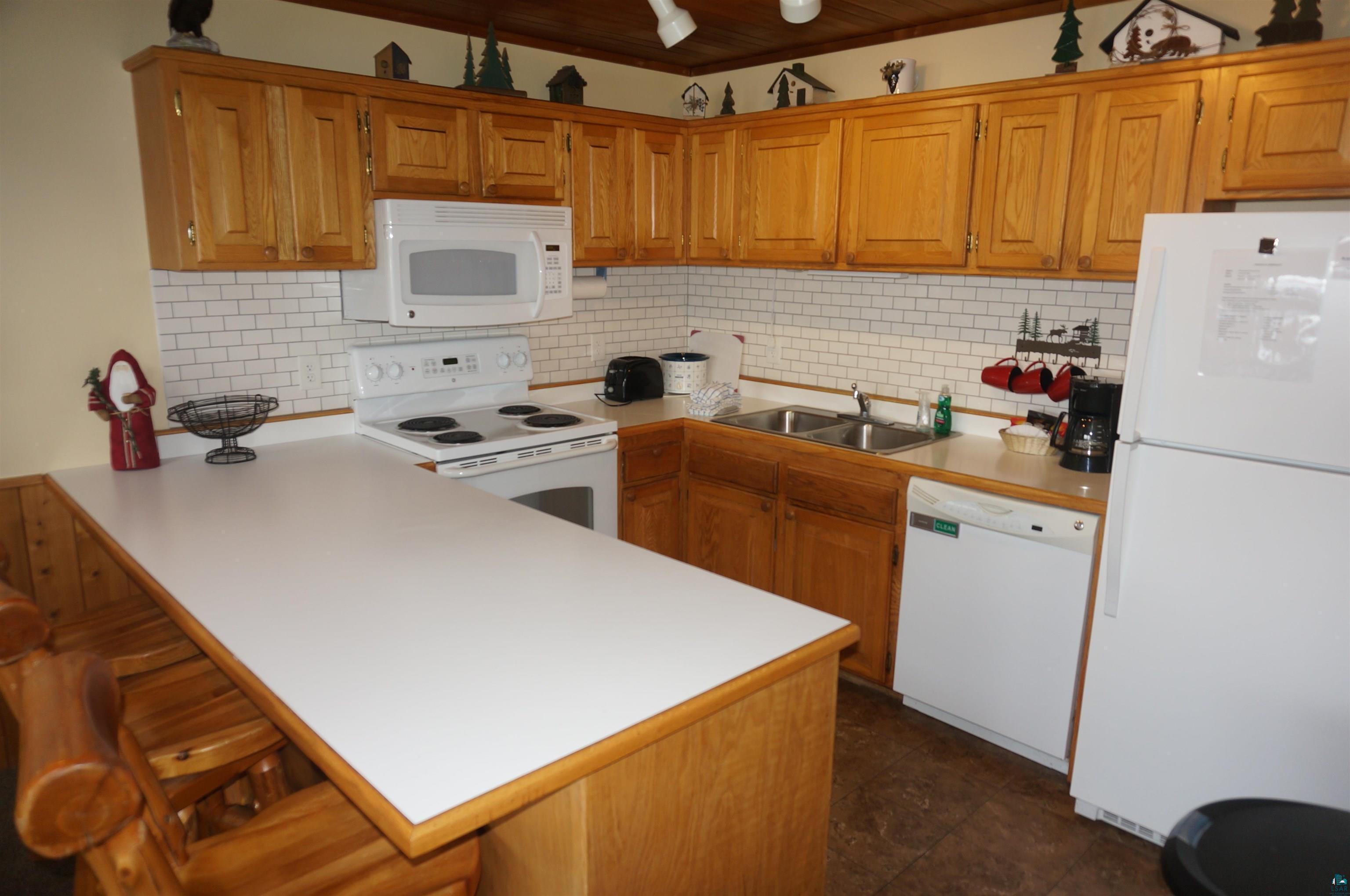 Image 3: Kitchen with a peninsula, white appliances, a sink, and backsplash, Kitchen