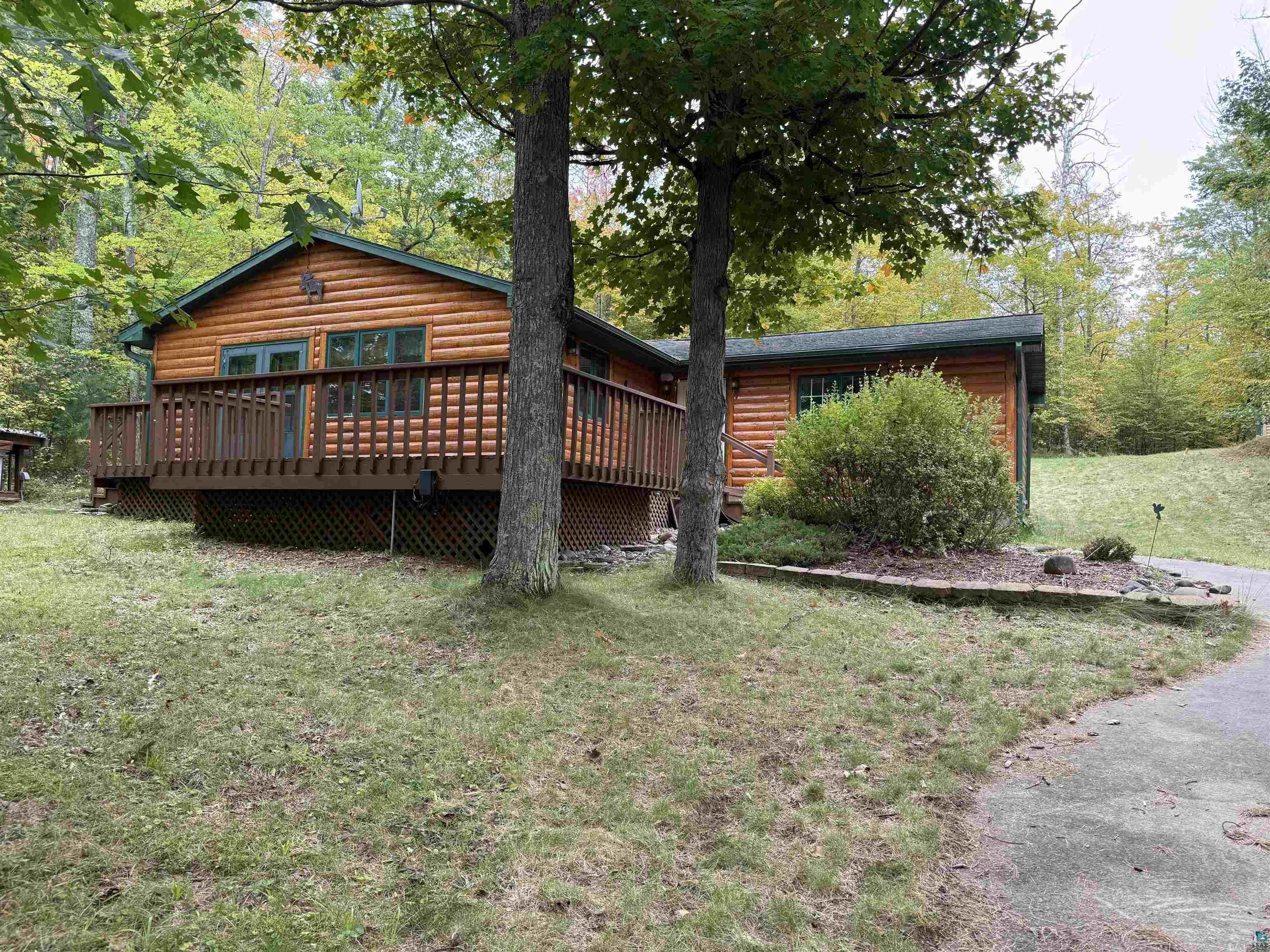 Image 0: Rear view of property with a deck, faux log siding, and a yard, Back Of Structure
