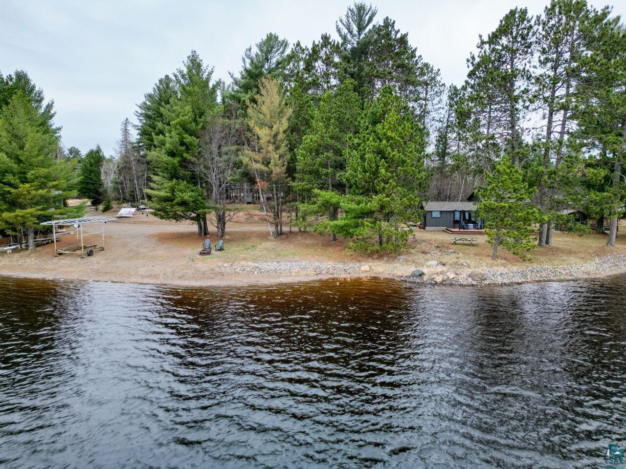 Image 0: Waterfront property featuring a dark-colored cabin with a small deck and a picnic table, View
