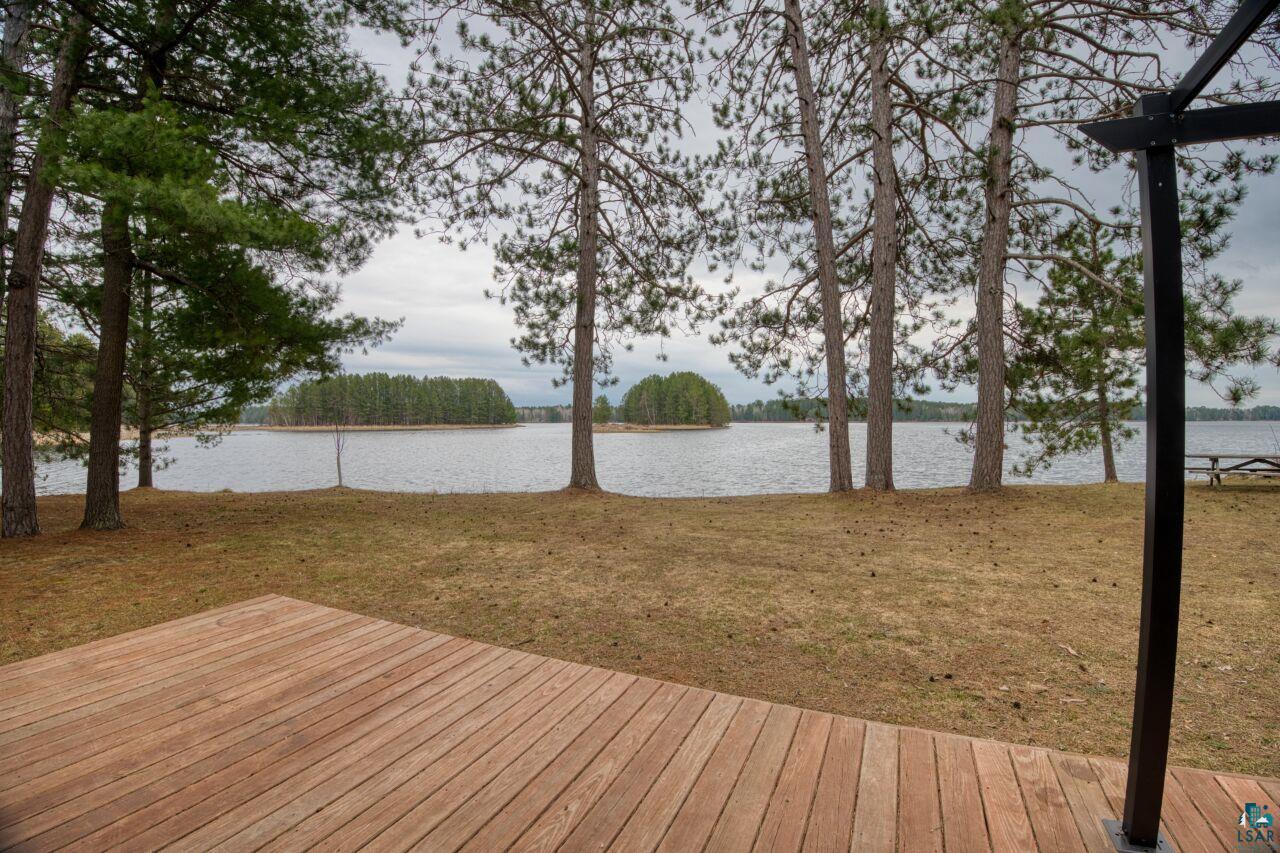 Image 3: Expansive wood deck overlooking a tranquil lake with mature pine trees, Deck