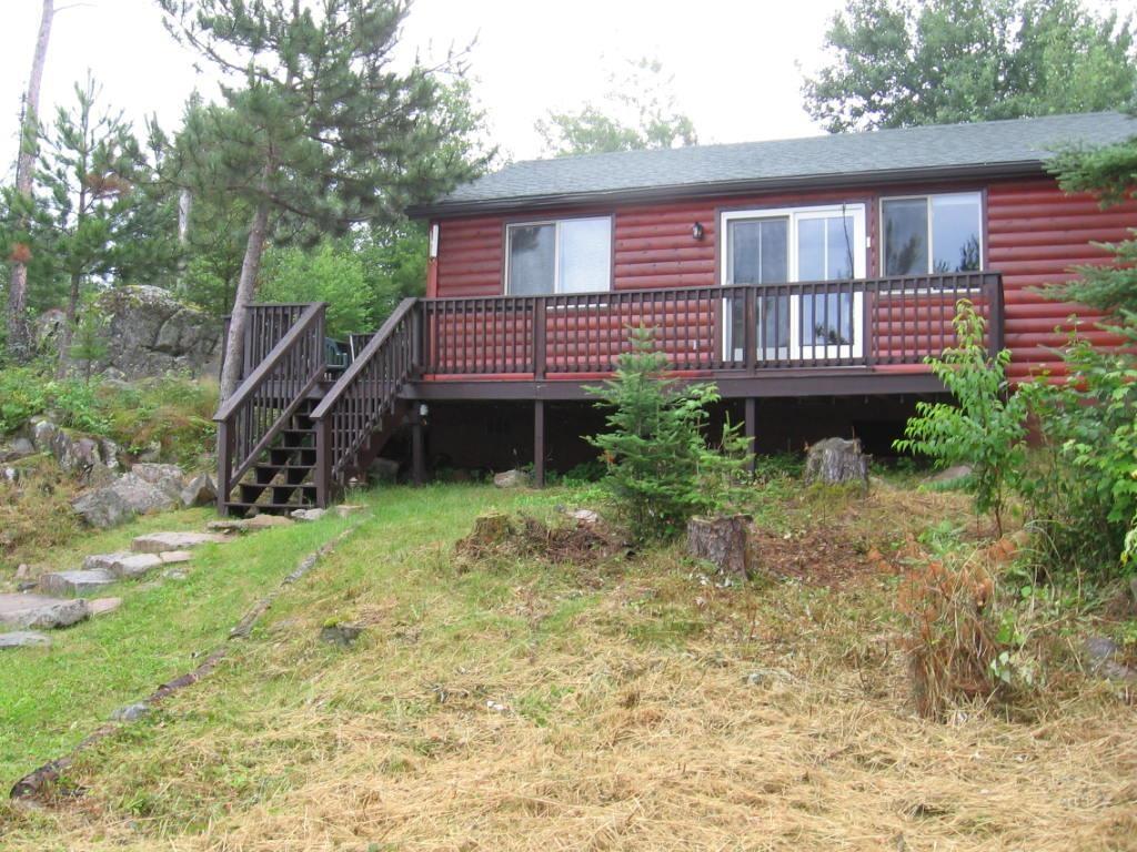 Image 0: view of property with log veneer siding, a deck, stairs to dock, Lakeside